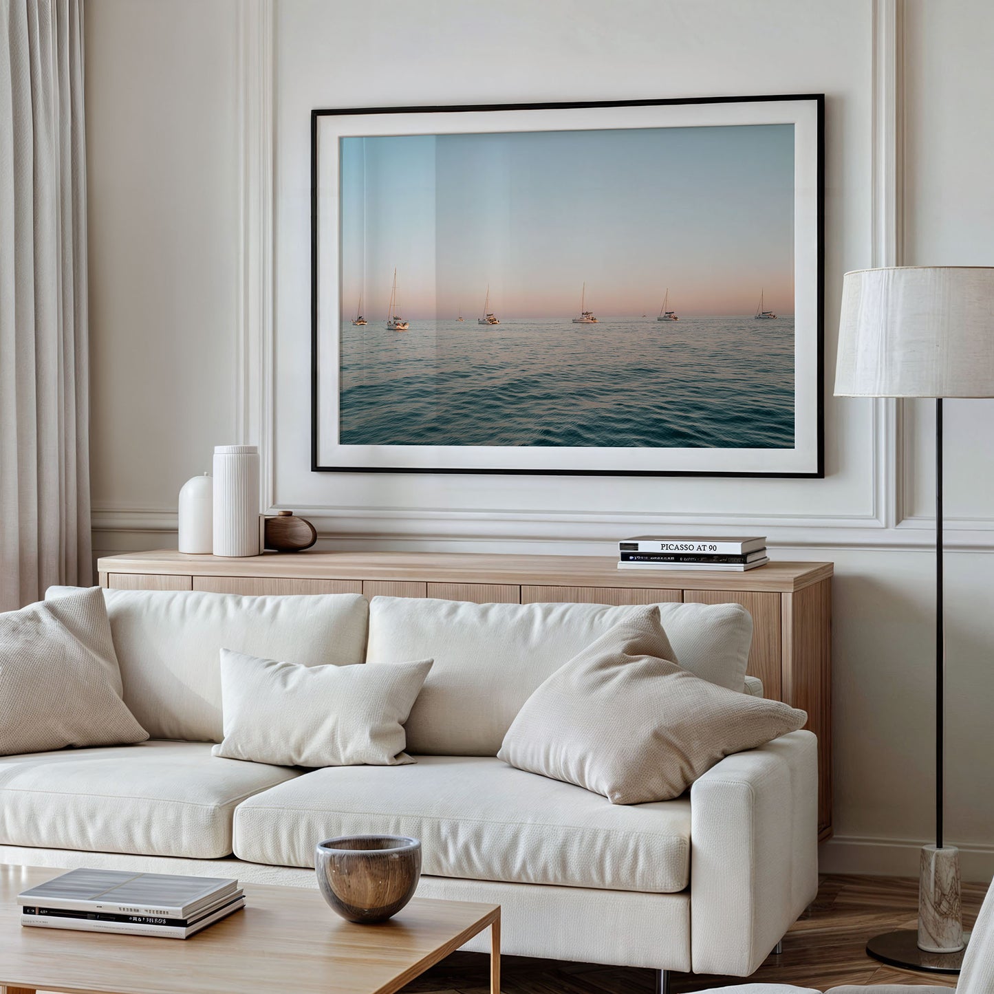 Neutral living room with beige sofa, wood furniture, and a large framed Sunset Formation sailboat photo.