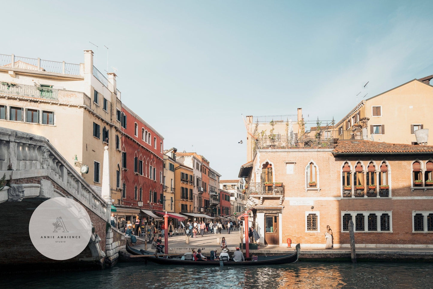 Scenic view from A Day in Venice: Canal with gondola, historic buildings, and stone bridge under a clear sky.