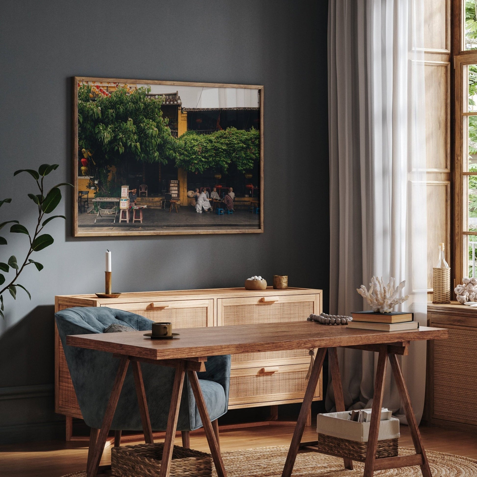 Dark room with a large window for natural light., featuring the Afternoon in Hoi An print along with a wooden desk and velvet blue chair.