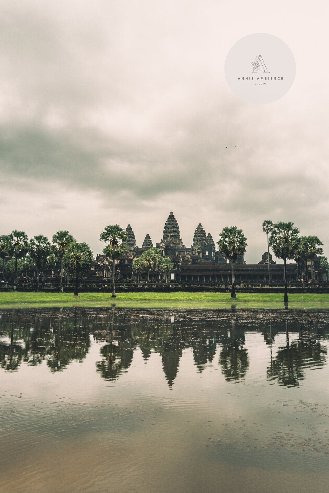 Angkor Wat with a cloudy sky reflected in water.