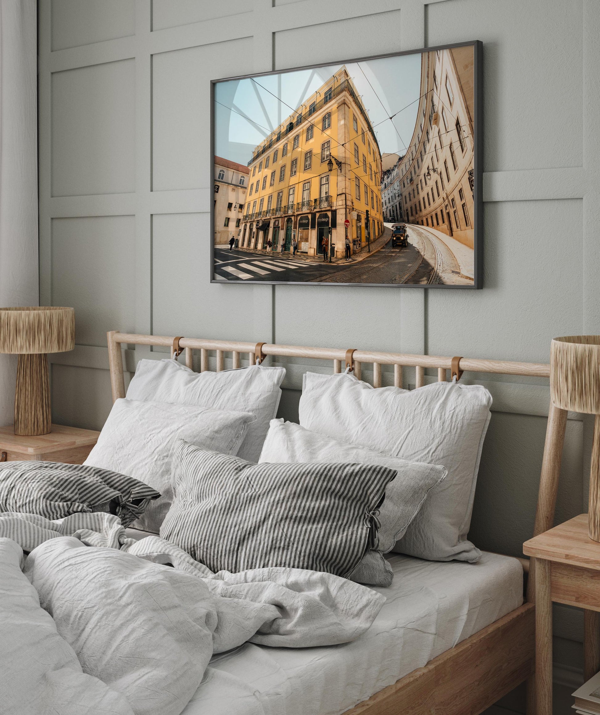 Cozy bedroom with the Baixa-Chiado wooden bed, gray bedding, and a framed cityscape above the paneled wall.