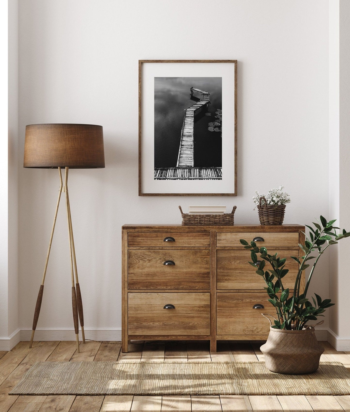 Minimalist room with a wooden dresser, floor lamp, plant, and Bamboo Dock Black and White photo on the wall.
