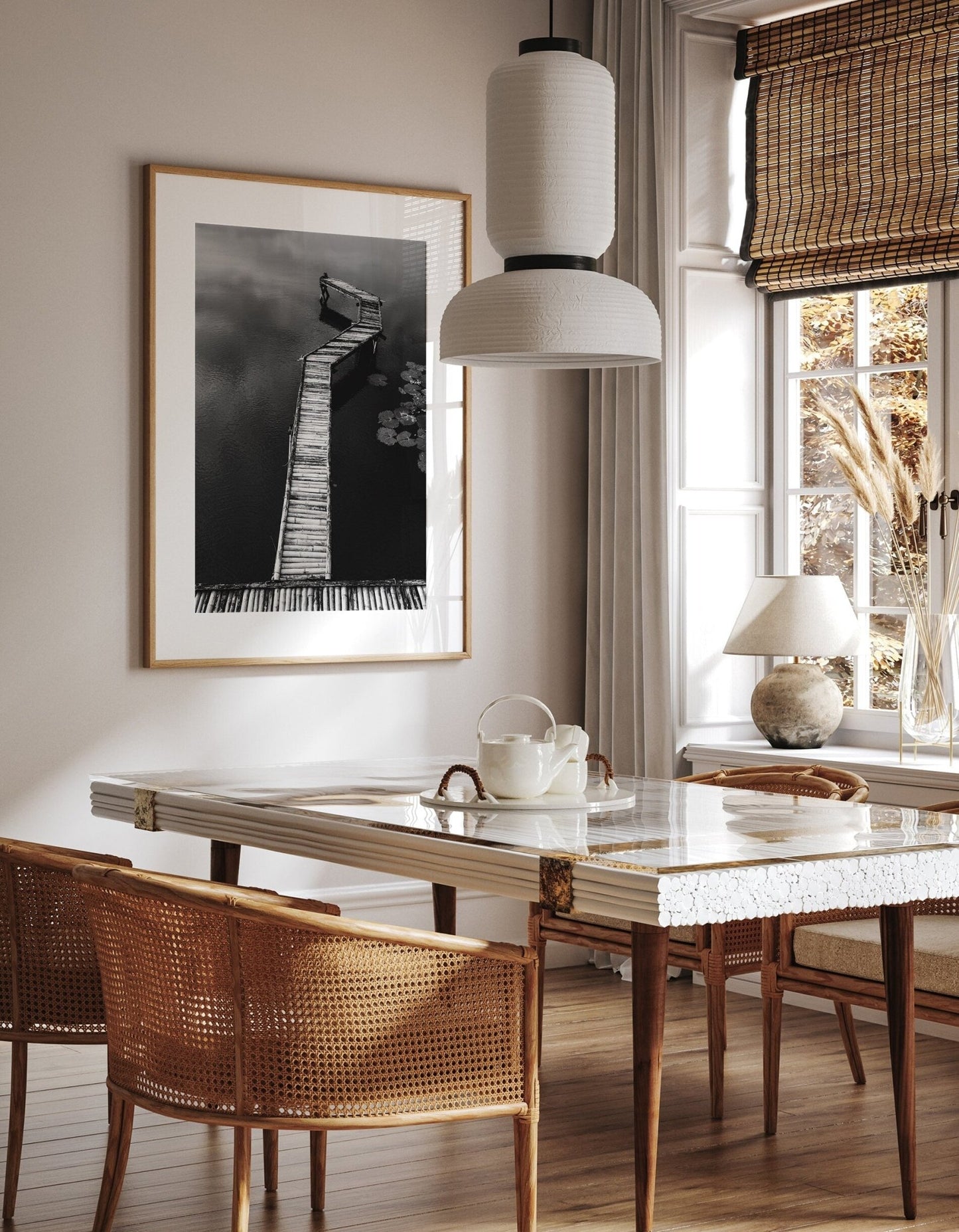 Dining area with a marble table, wicker chairs, and pendant light. Bamboo Dock Black and White art on the wall.