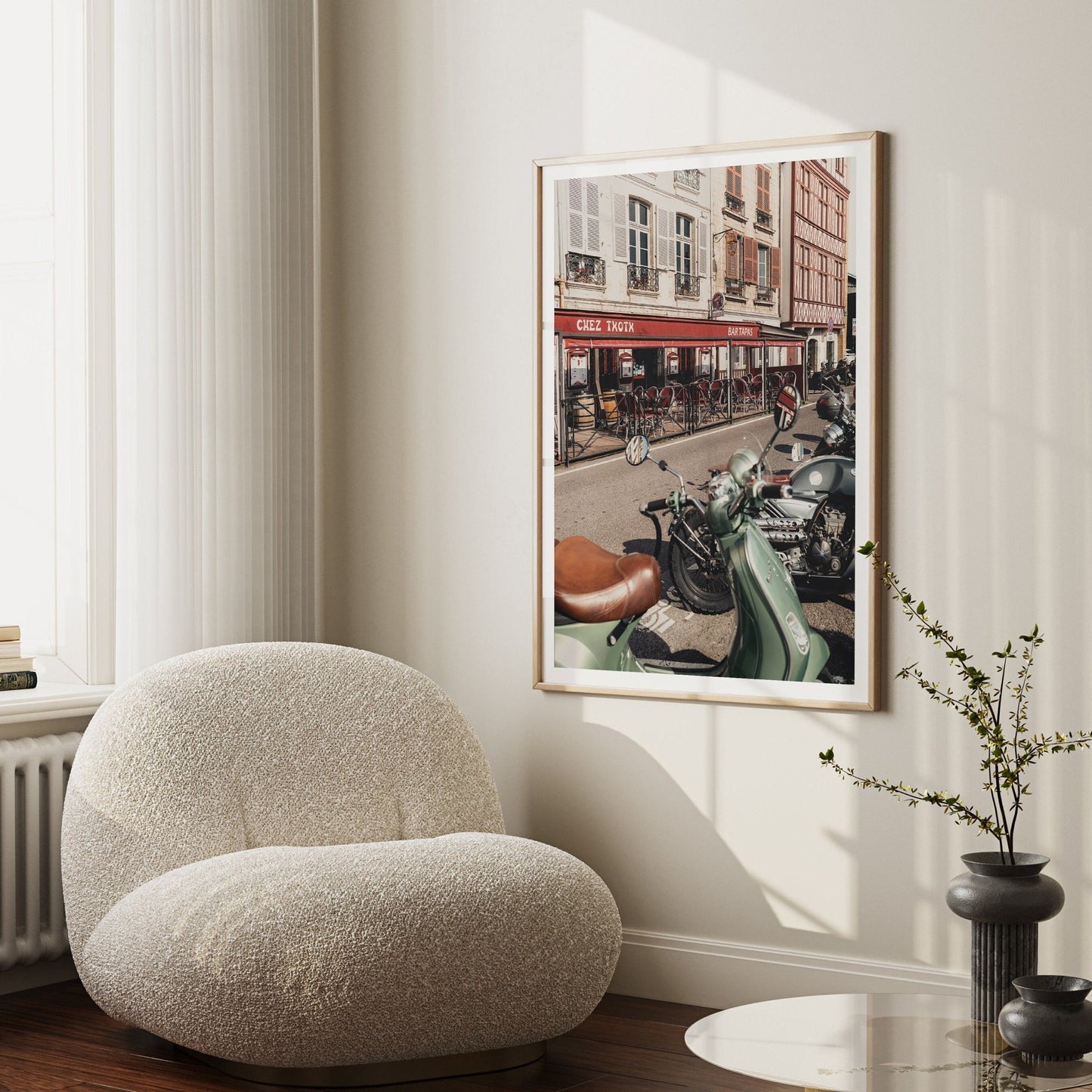 Cozy living room with a plush chair, modern side table, and Bayonne Vespa artwork depicting bikes and a café scene.