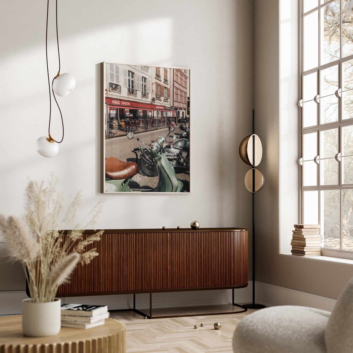 A modern living room features a Bayonne Vespa sideboard, hanging light fixture, window, and framed street photo on the wall.