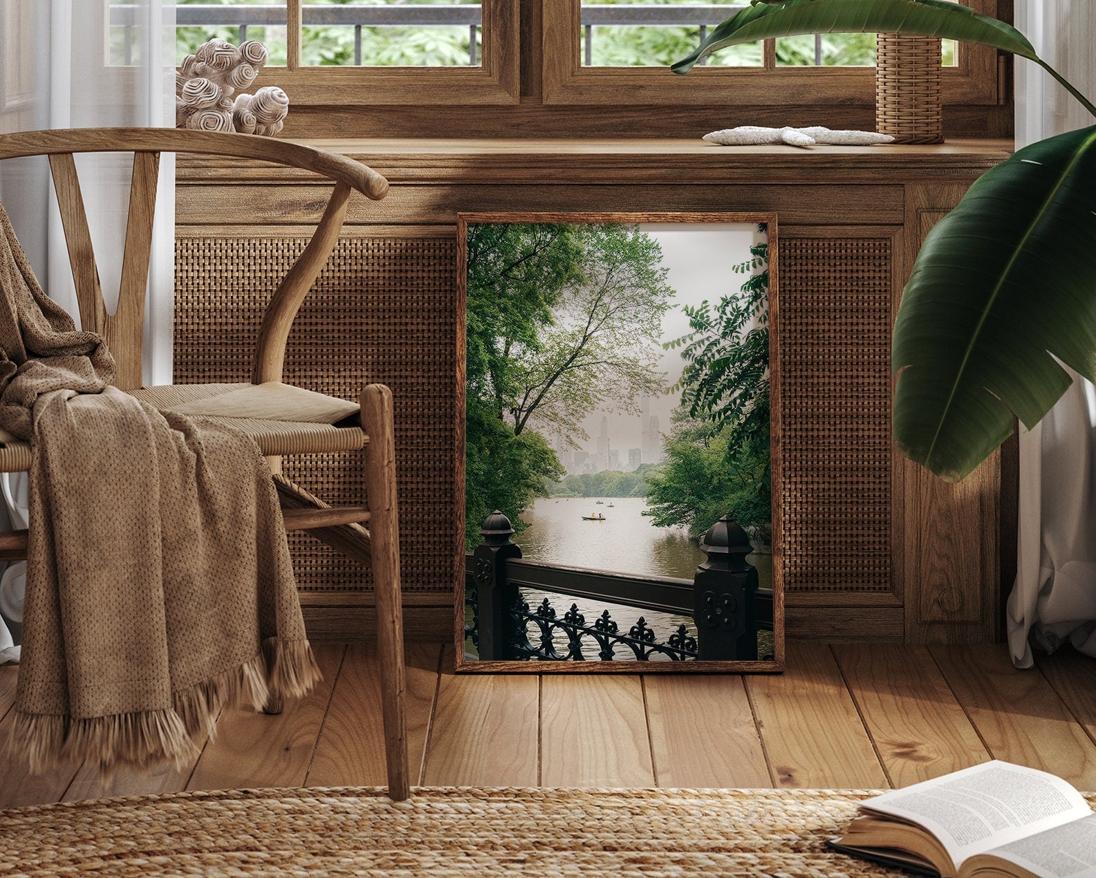 The Beyond the Bridge mirror leans against a wooden wall, reflecting a park with trees, a pond, and city skyline. Cozy decor.