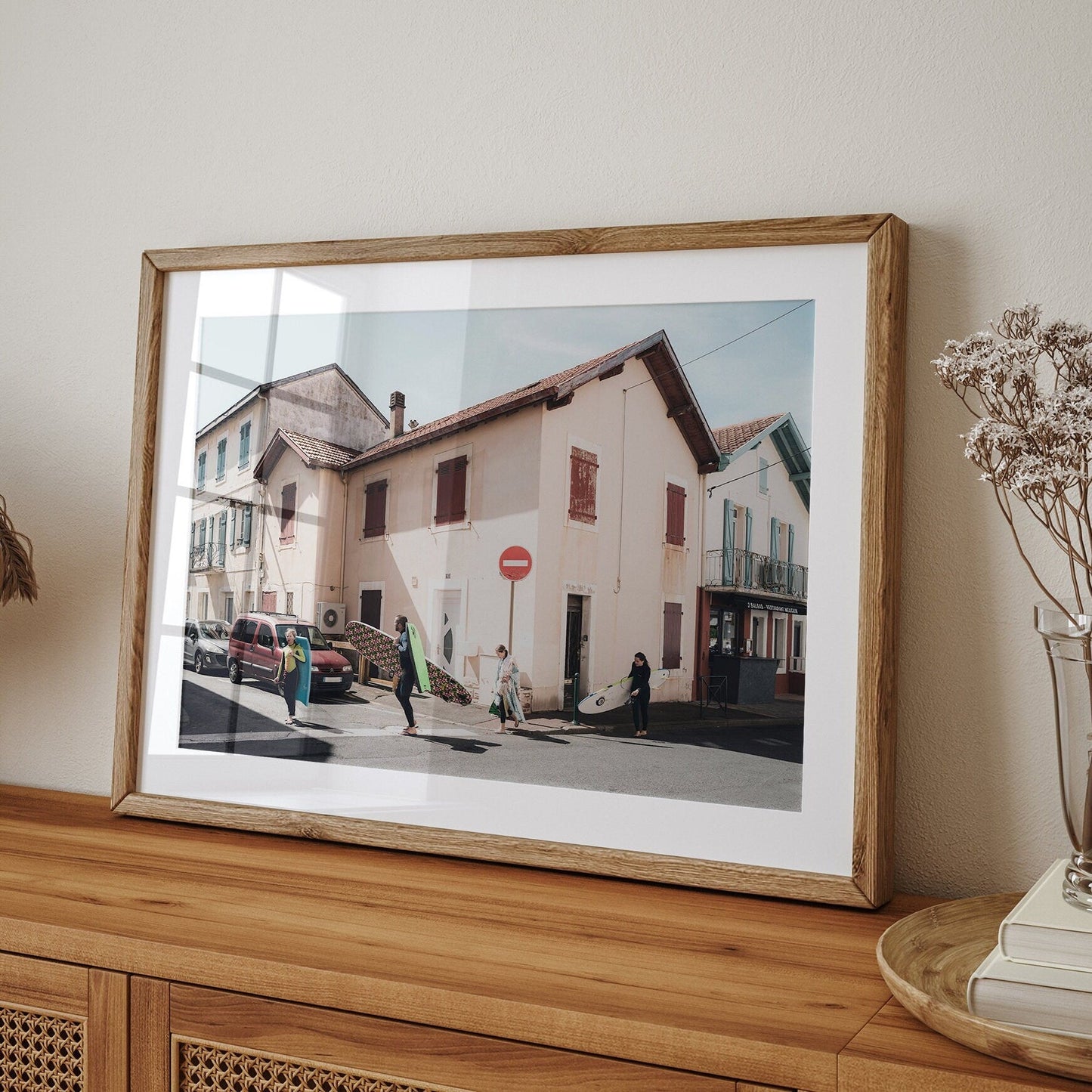 Biarritz Surfers photo shows surfers on a sunny street with quaint houses, displayed on a wooden sideboard.