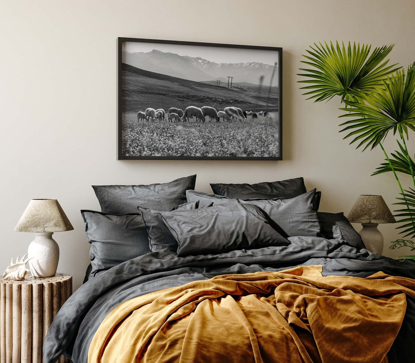 Cozy bed with grey and mustard bedding, two lamps, a plant, and Atlas Mountains I Black and White photo above.