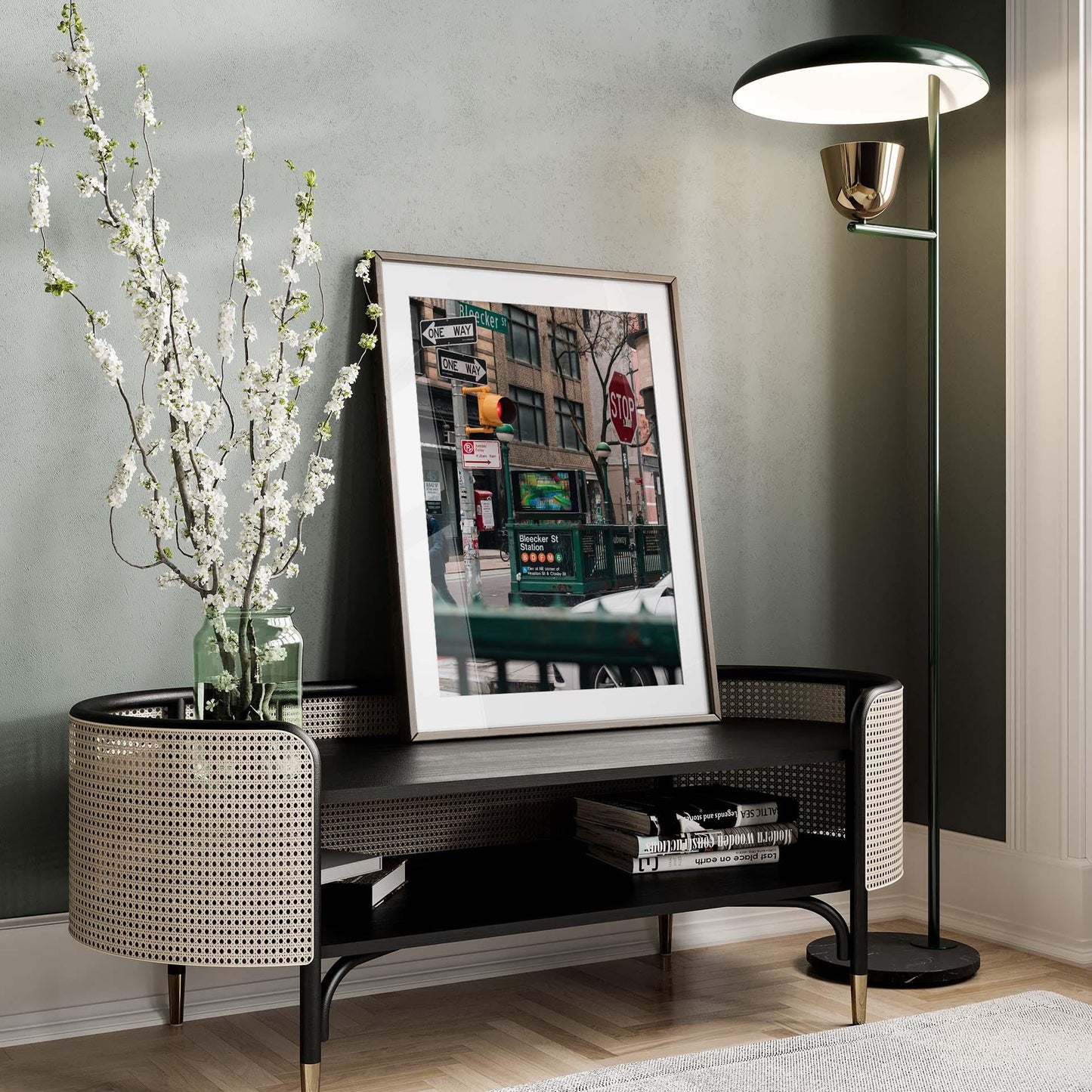Stylish room featuring Bleecker St. Station photo, a branch-filled vase on a console, and a tall floor lamp.