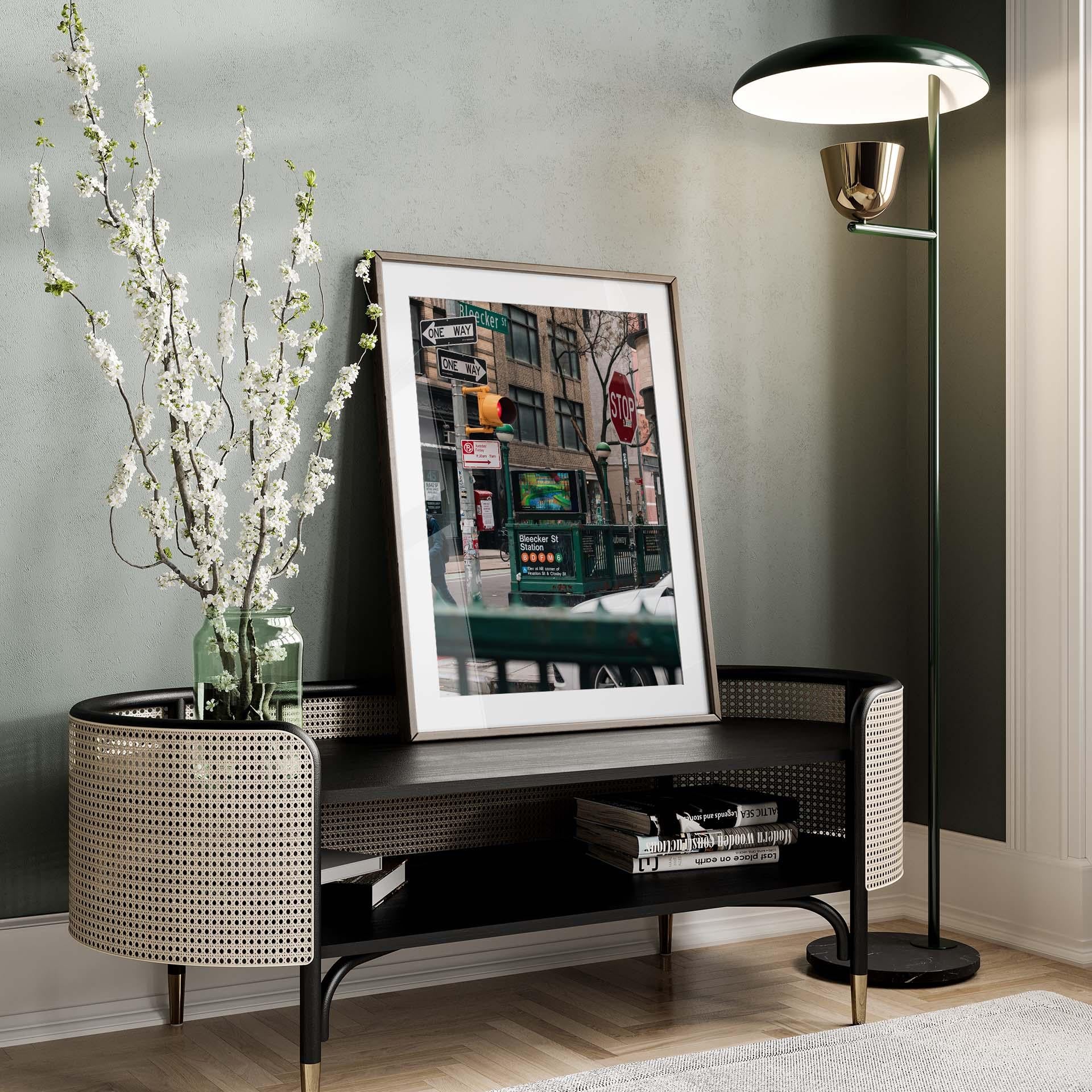 Stylish room featuring Bleecker St. Station photo, a branch-filled vase on a console, and a tall floor lamp.