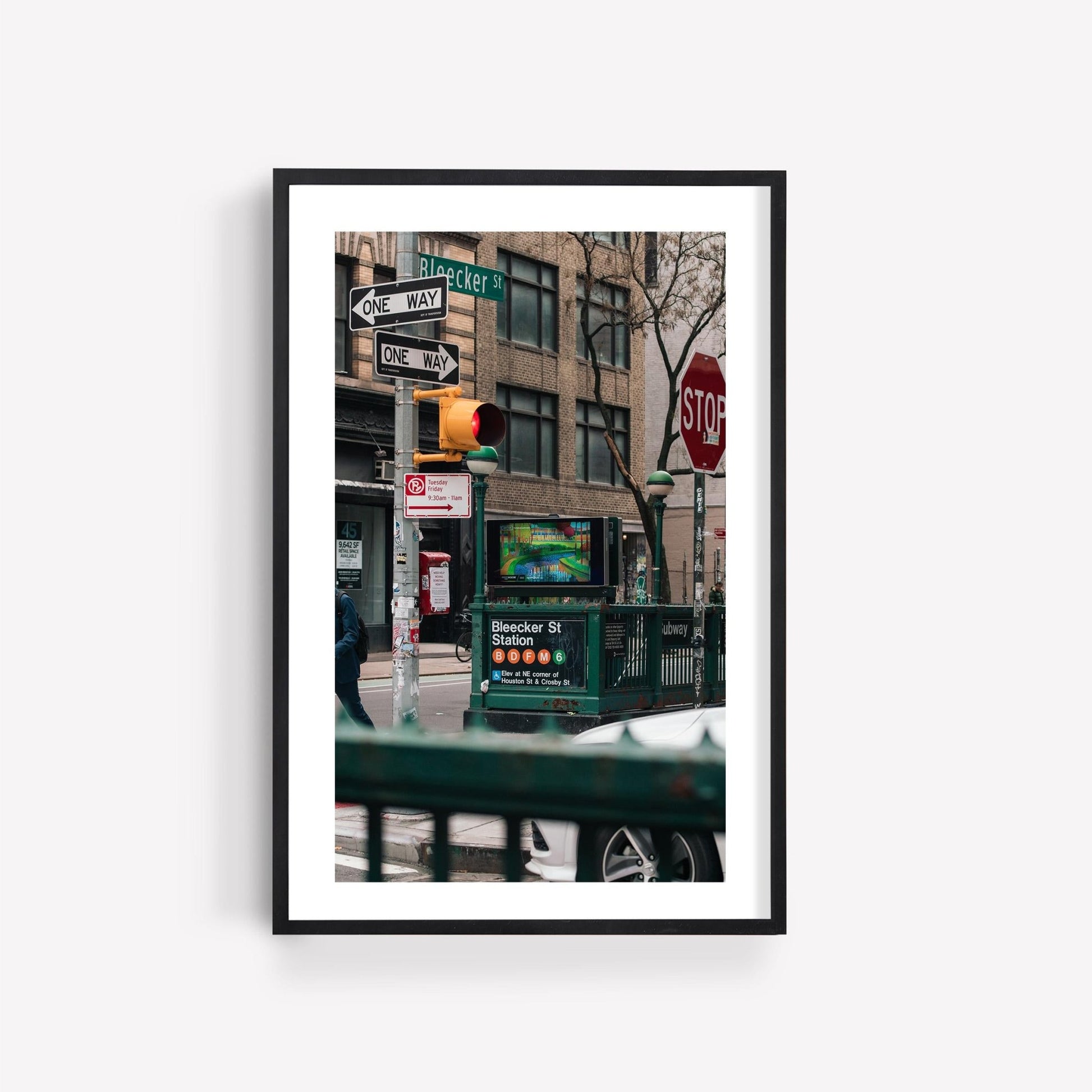 Framed photo titled Bleecker St. Station showing a city street with traffic lights, street signs, and a subway entrance.