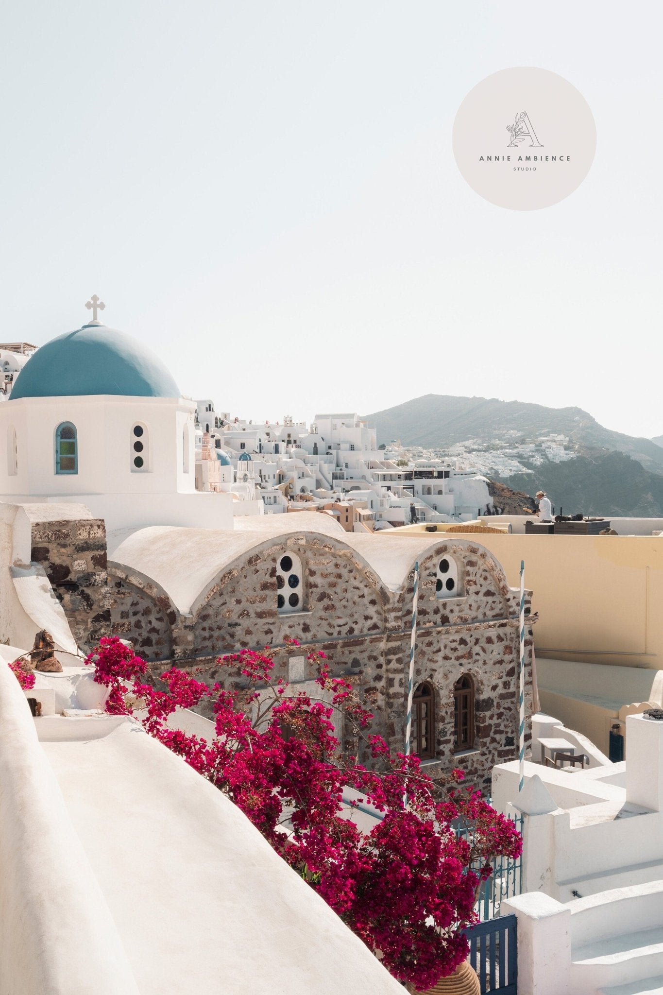 Scenic view of Santorini featuring Blue Dome, white buildings, and vibrant pink flowers in the foreground.