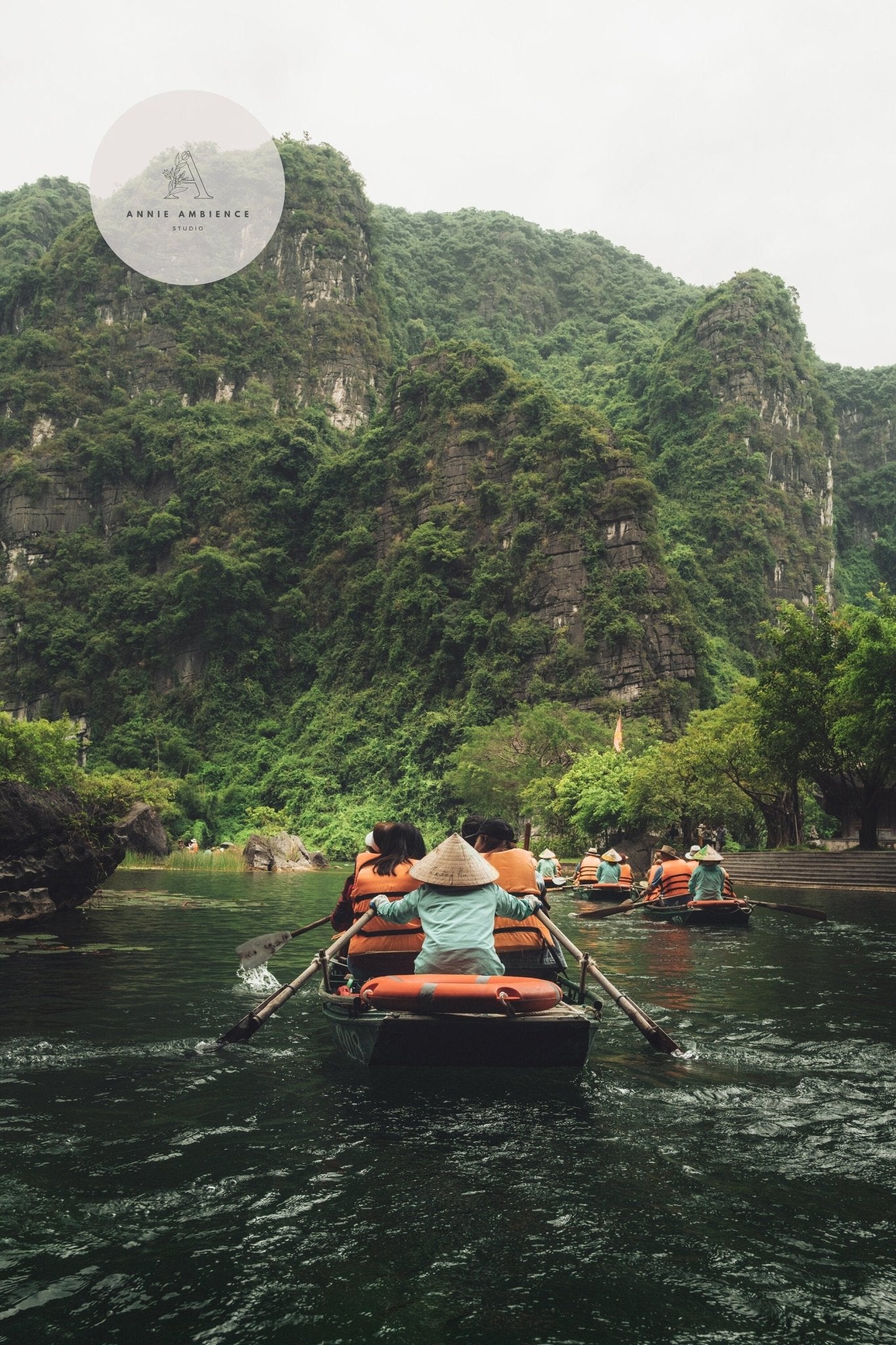 People using Boat Row on a river with lush green mountains around.