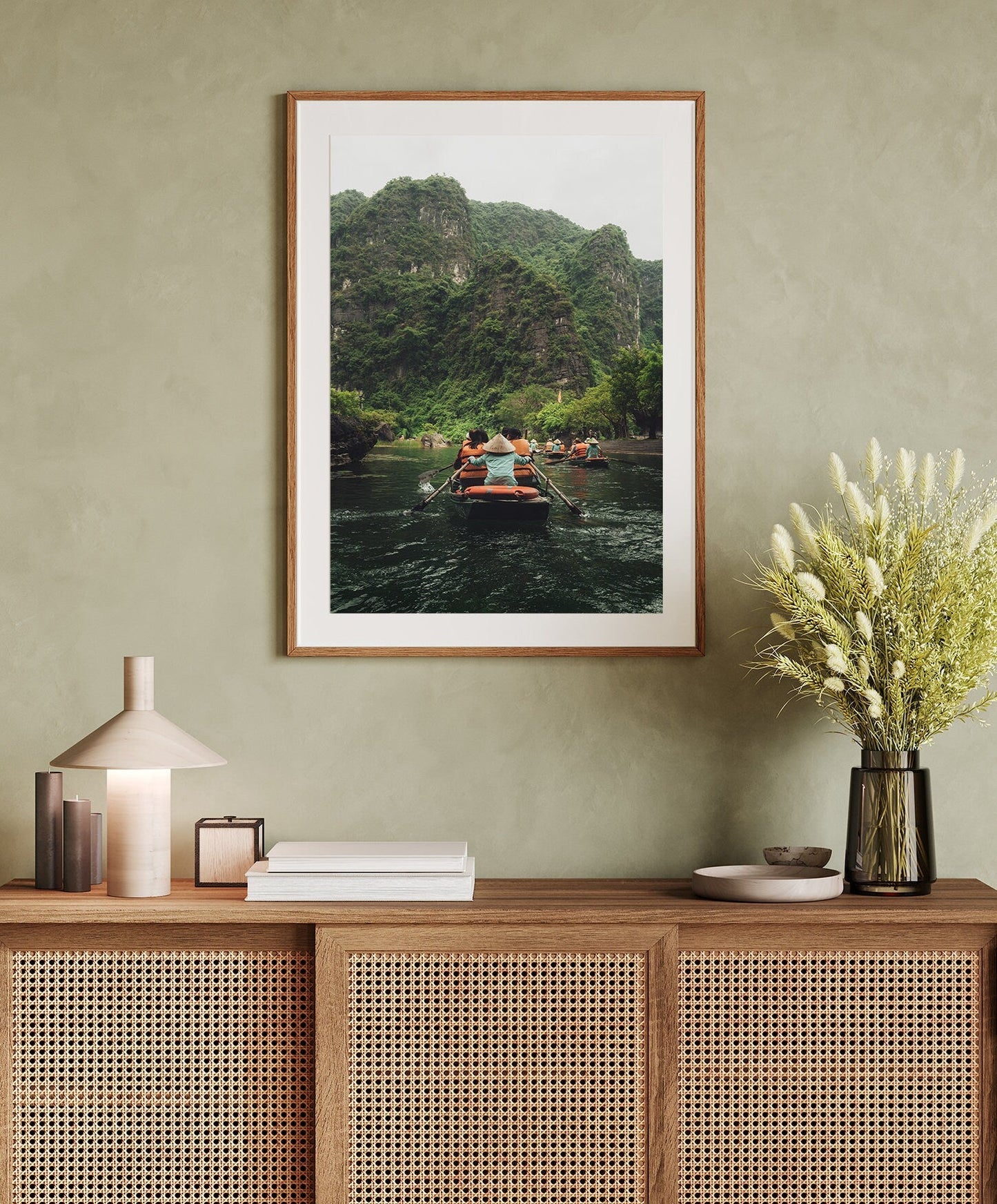 The Boat Row framed photo hangs above a cabinet with books, a lamp, and a vase of flowers.