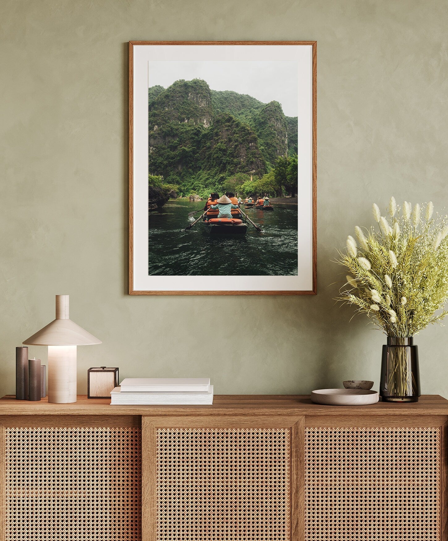 The Boat Row framed photo hangs above a cabinet with books, a lamp, and a vase of flowers.