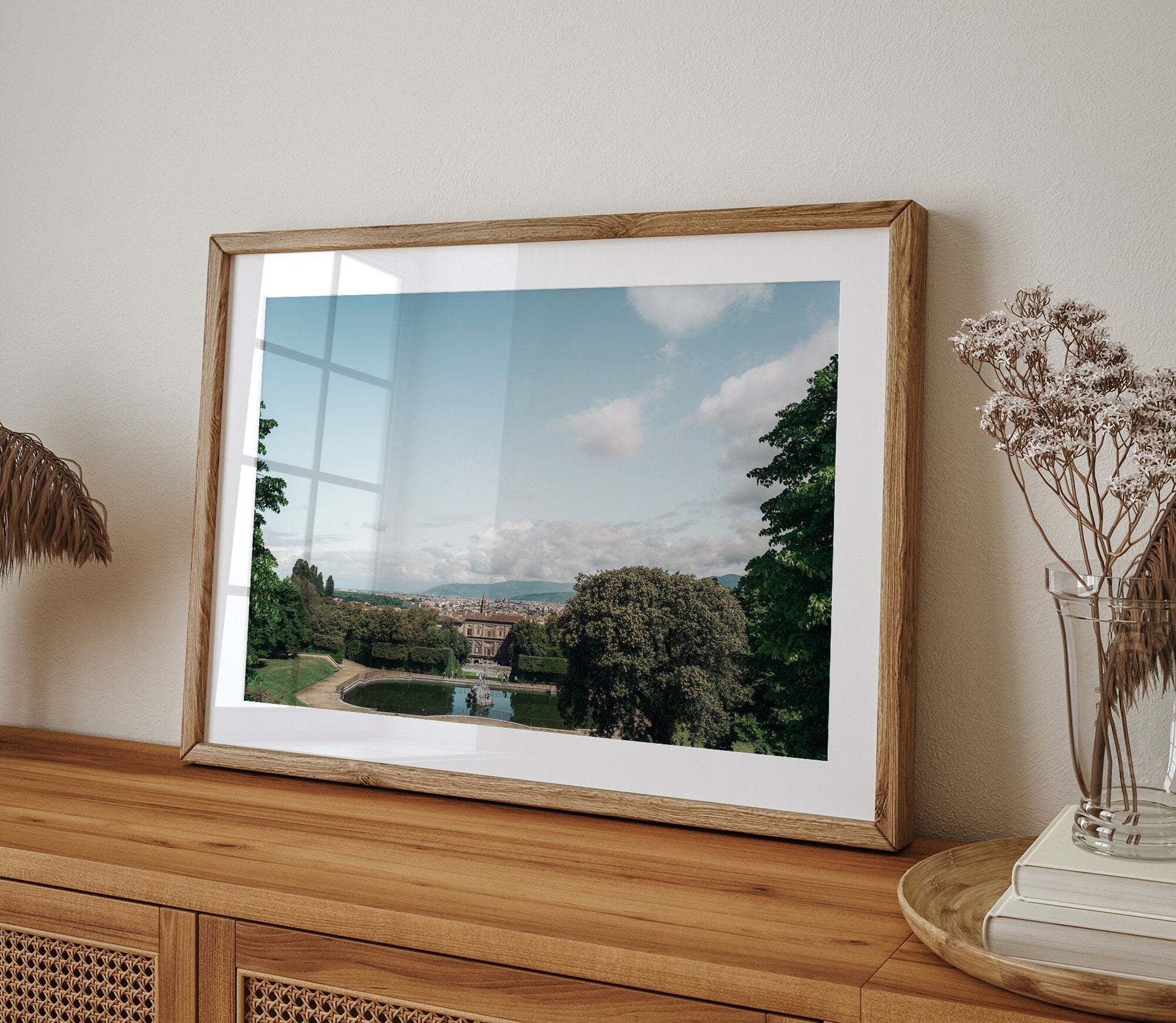 Framed photo of Boboli Gardens featuring trees and a distant building, displayed on a wooden table.