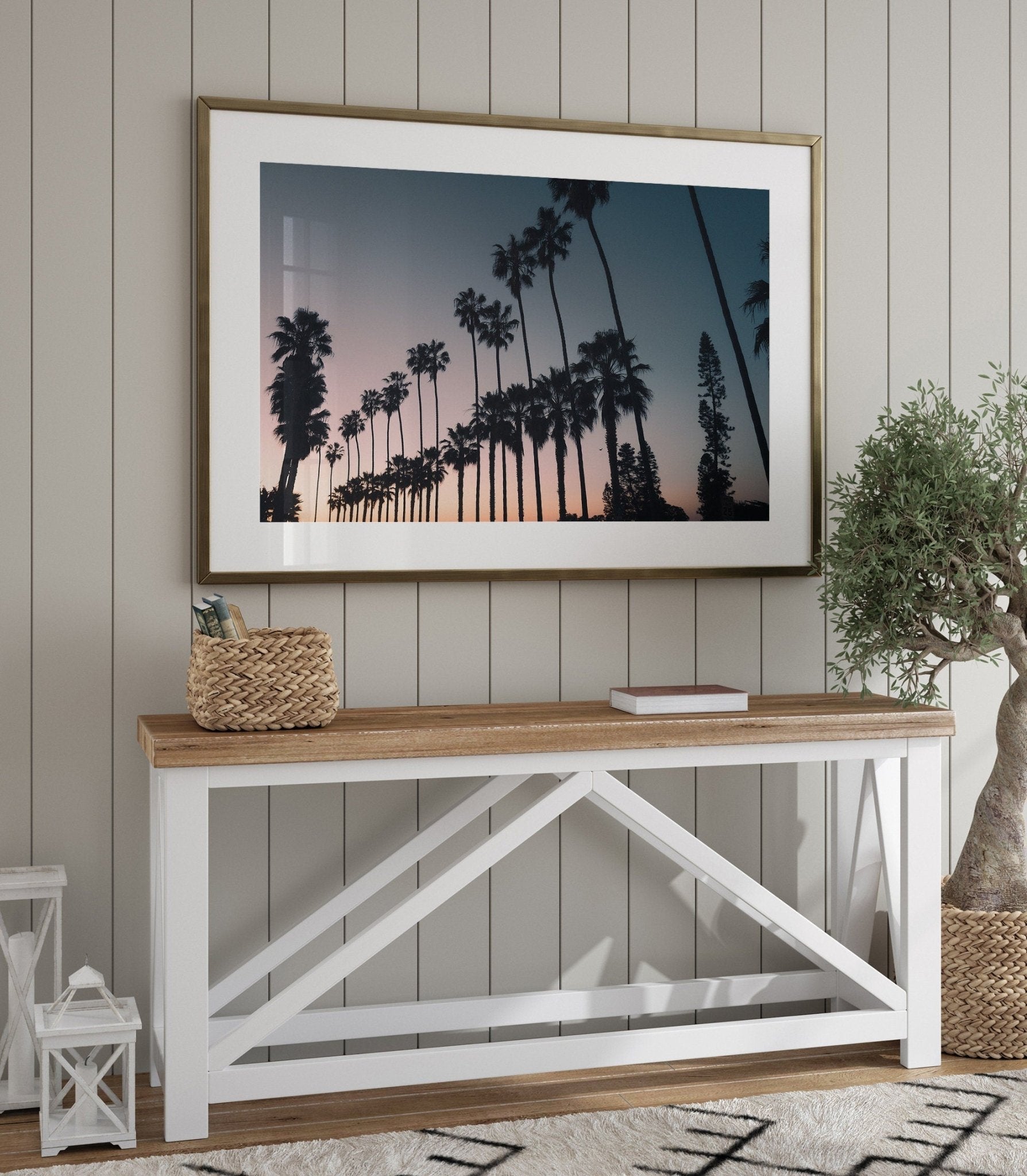 California Dreams photo above wooden table with basket, lanterns, and potted plant against a paneled wall.
