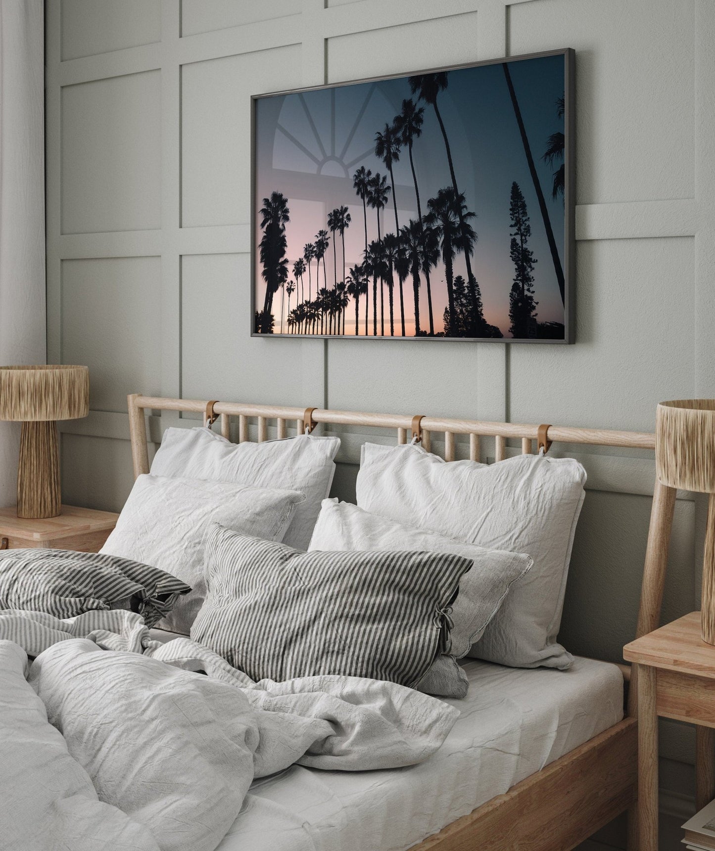 Cozy bedroom with a wooden bed, white bedding, and a California Dreams wall-mounted picture of palm trees at sunset.