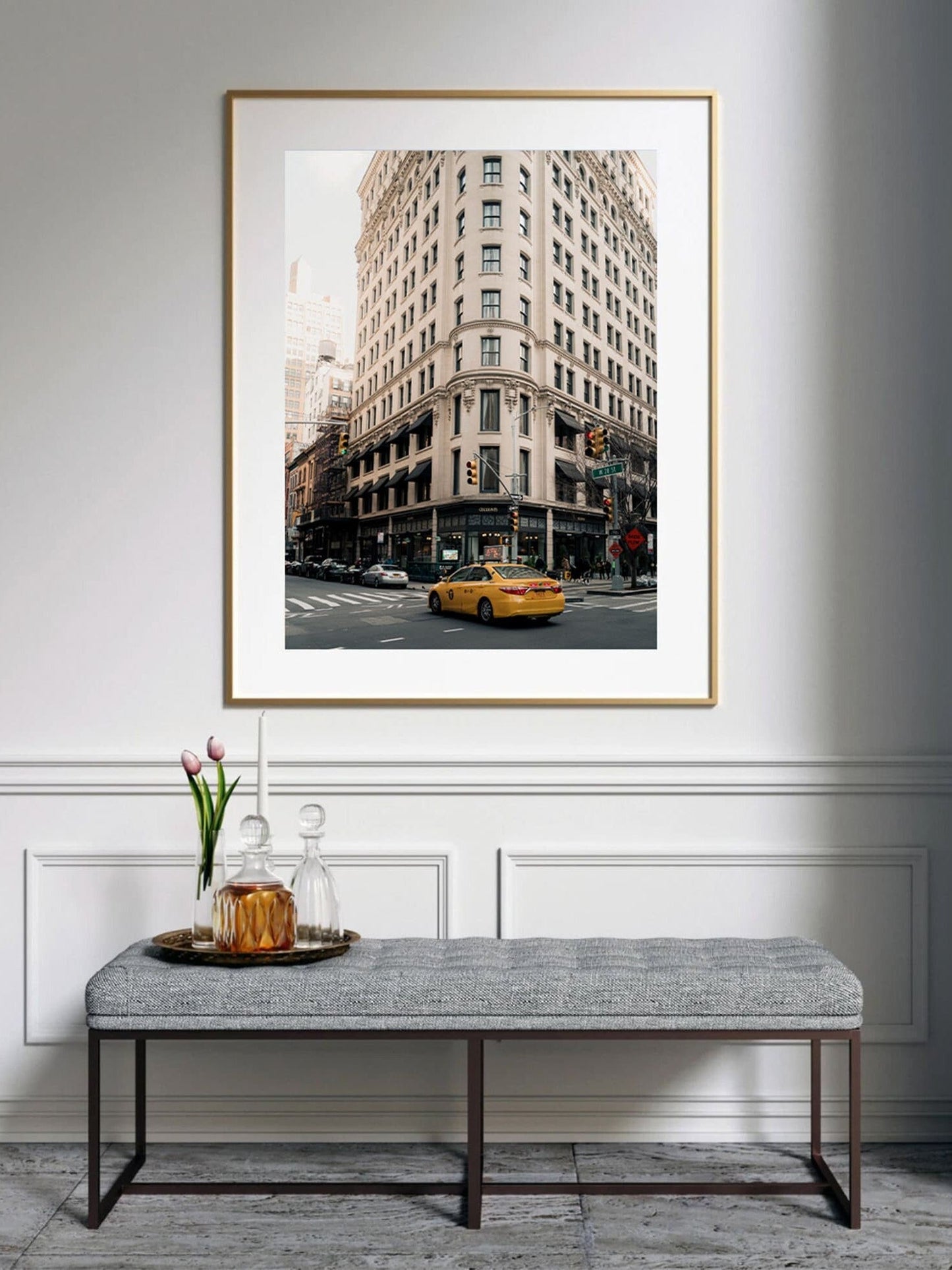 The Cecconis framed cityscape photo features a corner building with a yellow taxi above a bench with a tray and flowers.