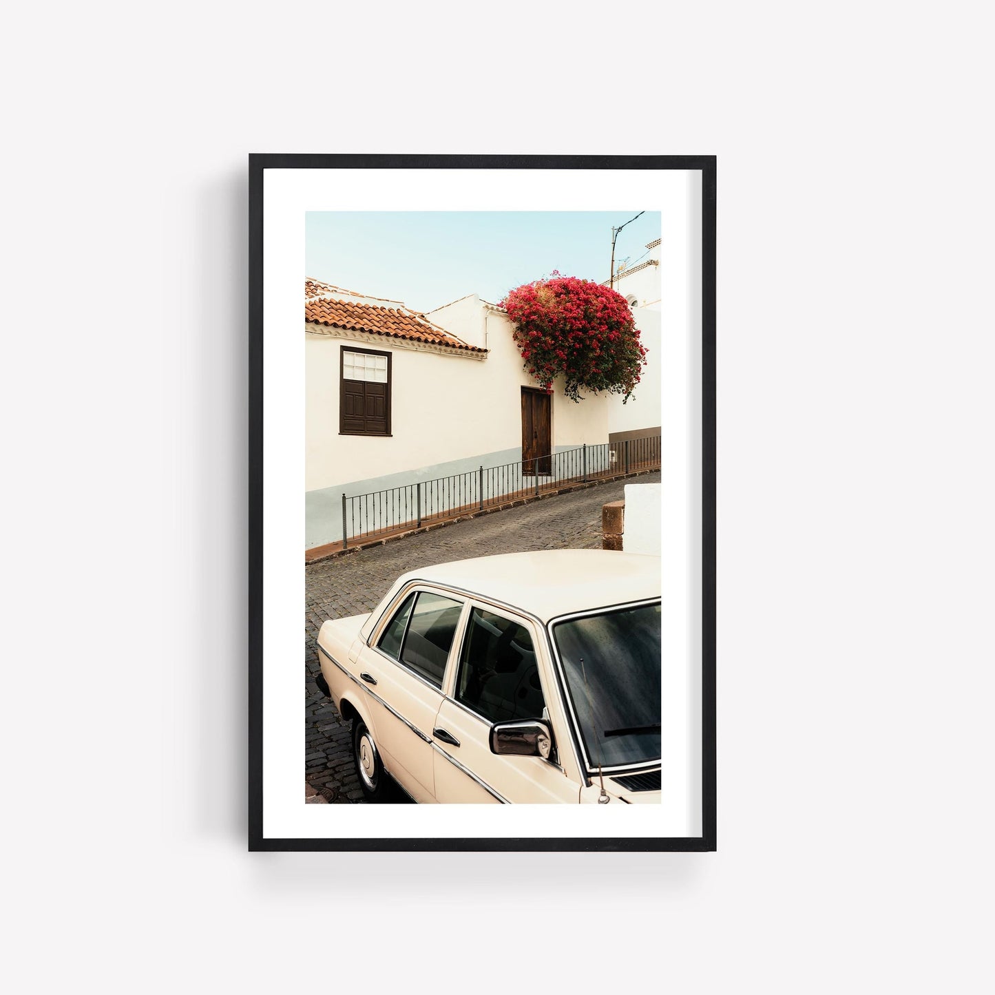 Classic in Bloom: Framed photo of a vintage white car by a house with red roof flowers under a clear sky.