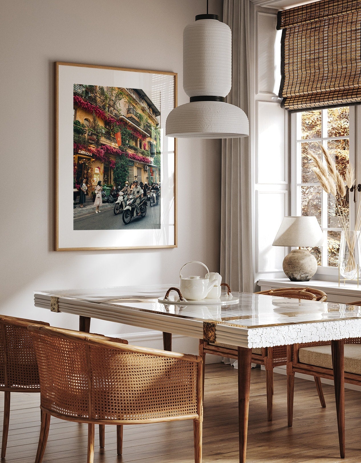 Elegant dining space with a marble table, wicker chairs, and Colors of Hanoi wall art under soft lighting.