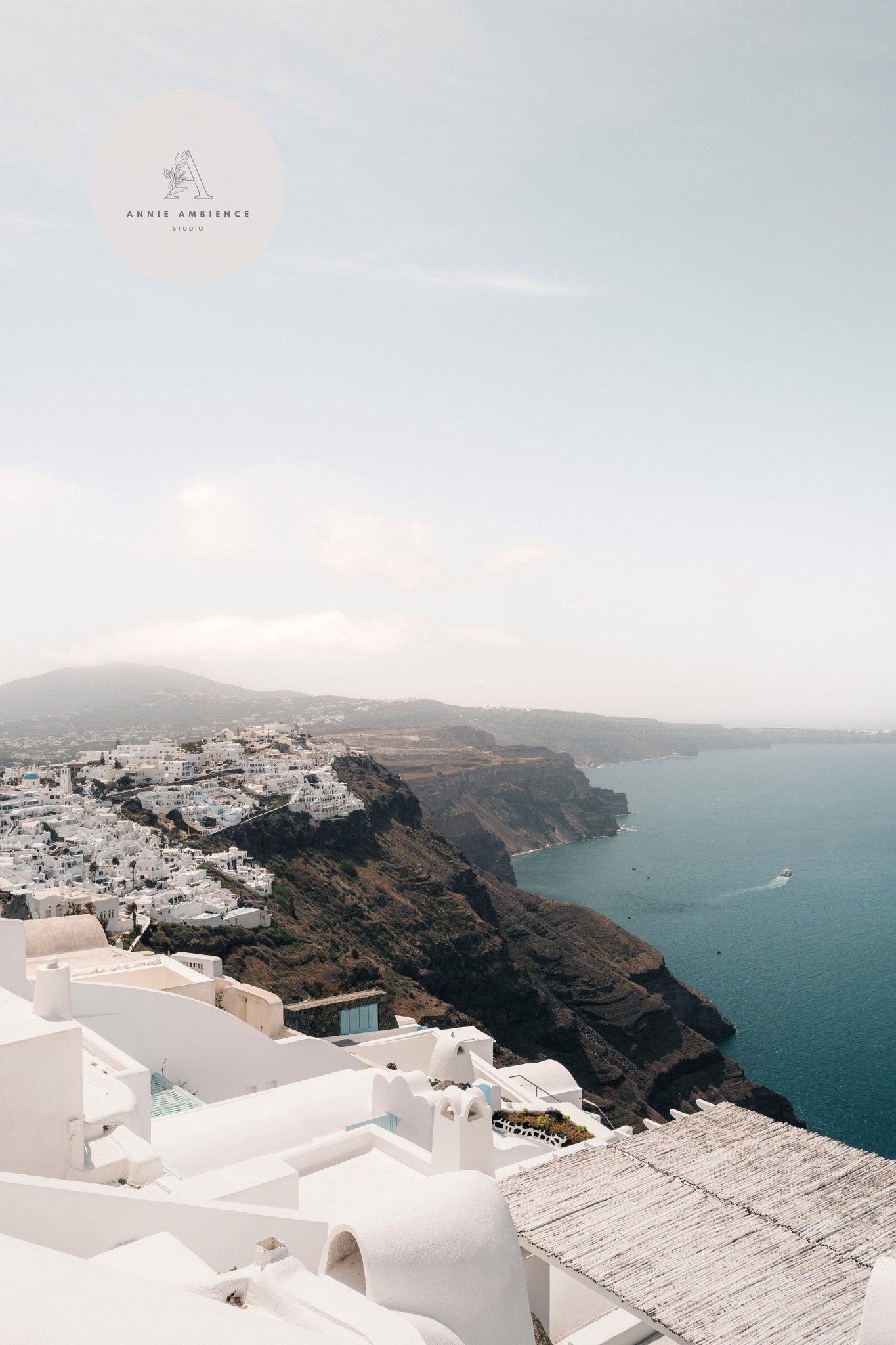Colors of Santorini: Coastal view with white cliffside buildings under a clear sky.