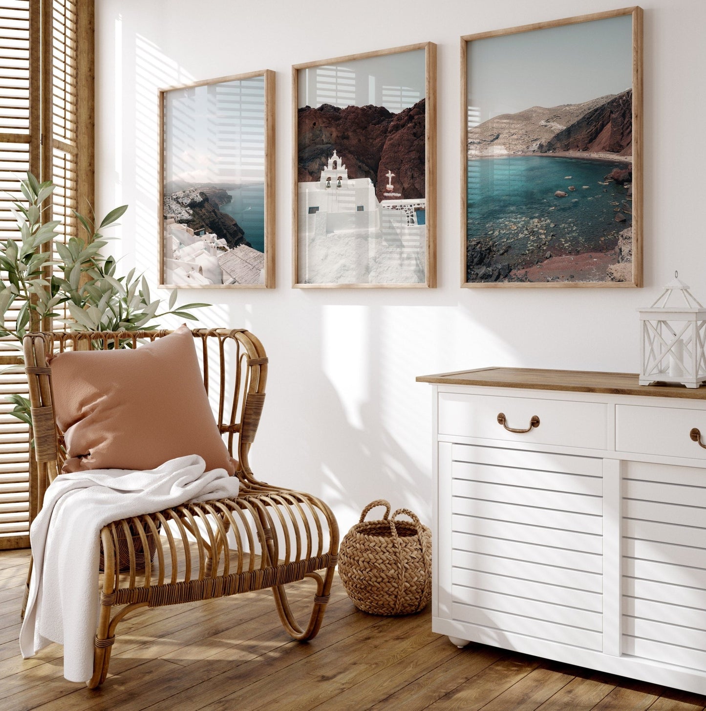 A cozy room with a wicker chair, cushioned pillow, and framed Colors of Santorini photo on a white wall.