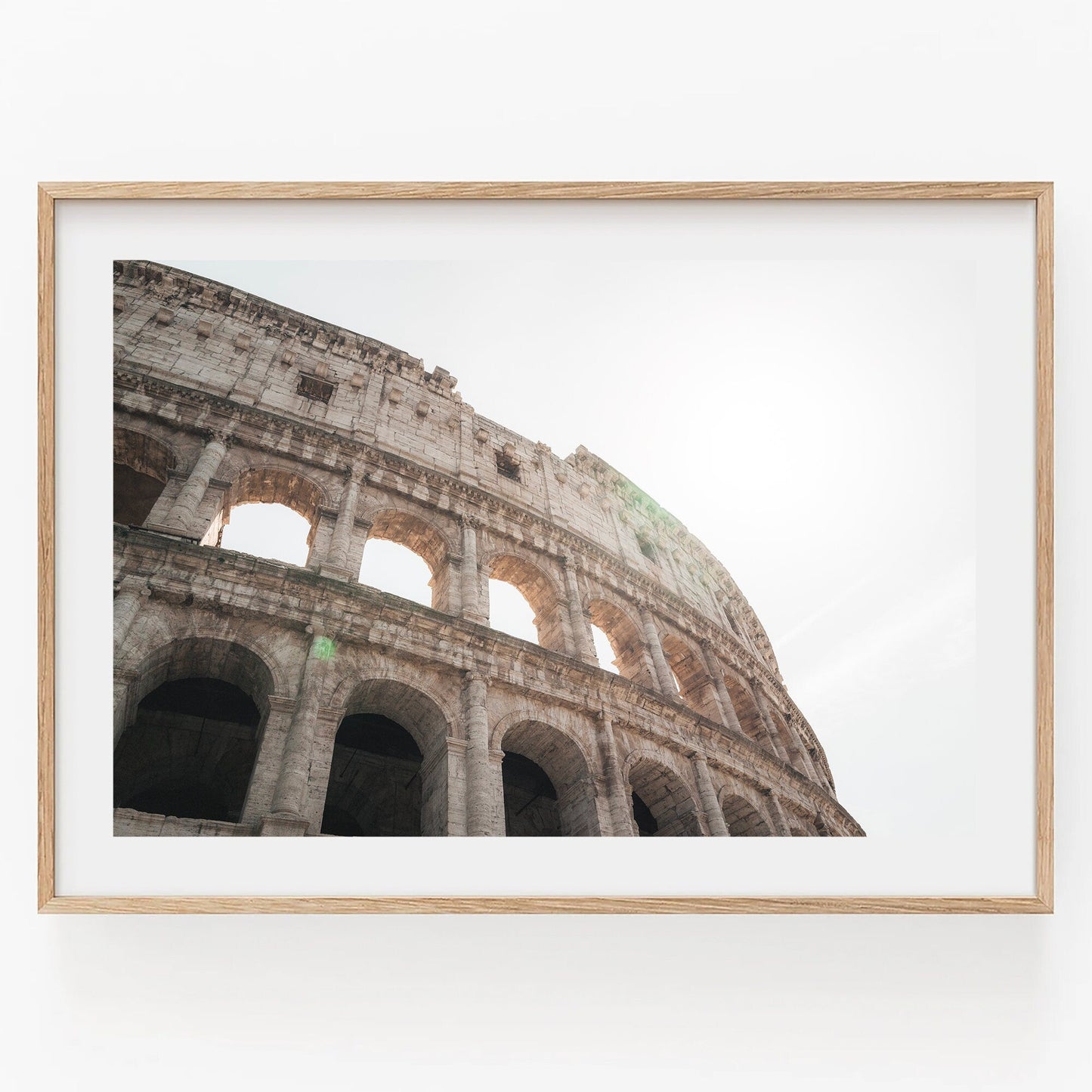 Framed Colosseum I photo with sunlight streaming through its arches against a clear sky.