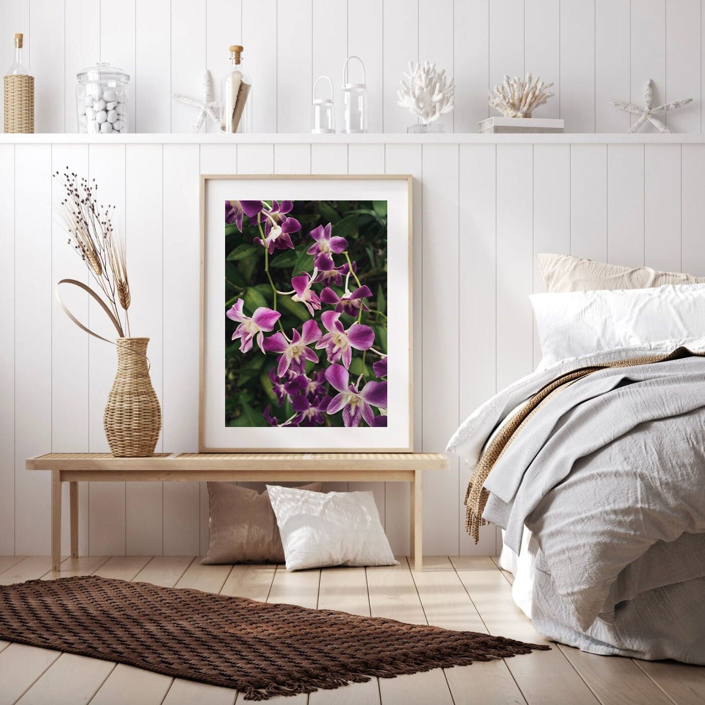 Bedroom with a wooden bench displaying a framed Purple Orchids picture, neutral tones, wicker vase, and woven rug.