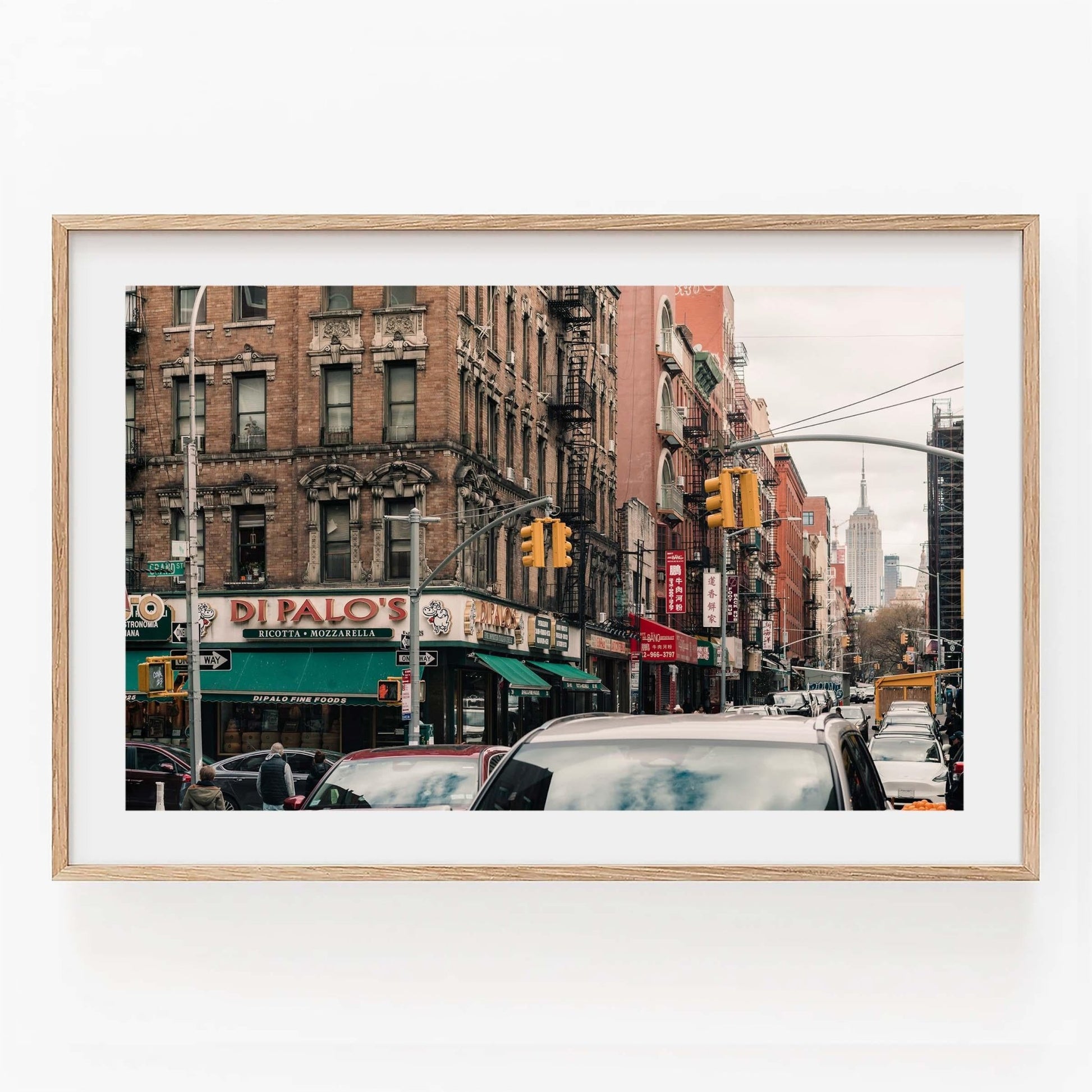 Framed city street scene with buildings, traffic, and a distant landmark view in Di Palos design.