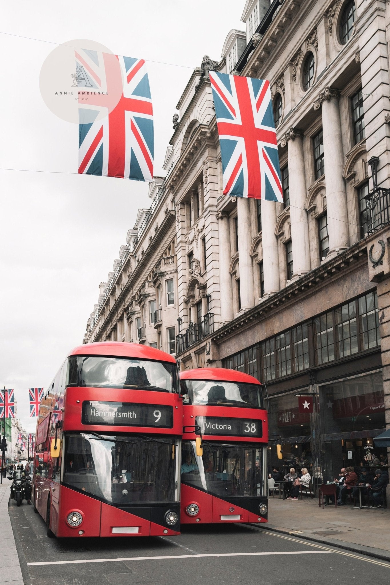 Two red Double-deckers on a London street, Union Jack flags hanging above.