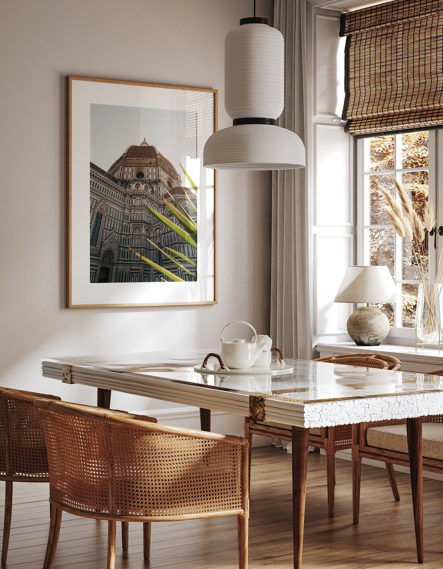 Cozy dining space with the Duomo framed photo, wicker chairs, marble table, and white pendant light.
