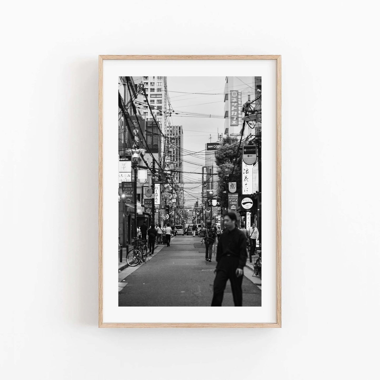Echoes of Osaka Black and White framed photo: busy city street scene with people, hung on a white wall.