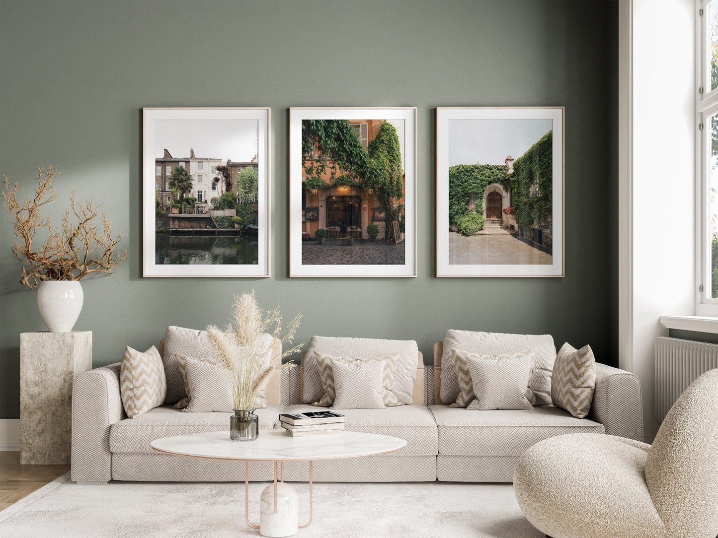 Living room with European Charm - Set of 3, a beige sofa, decorative pillows, a round table, and framed art on a muted green wall.