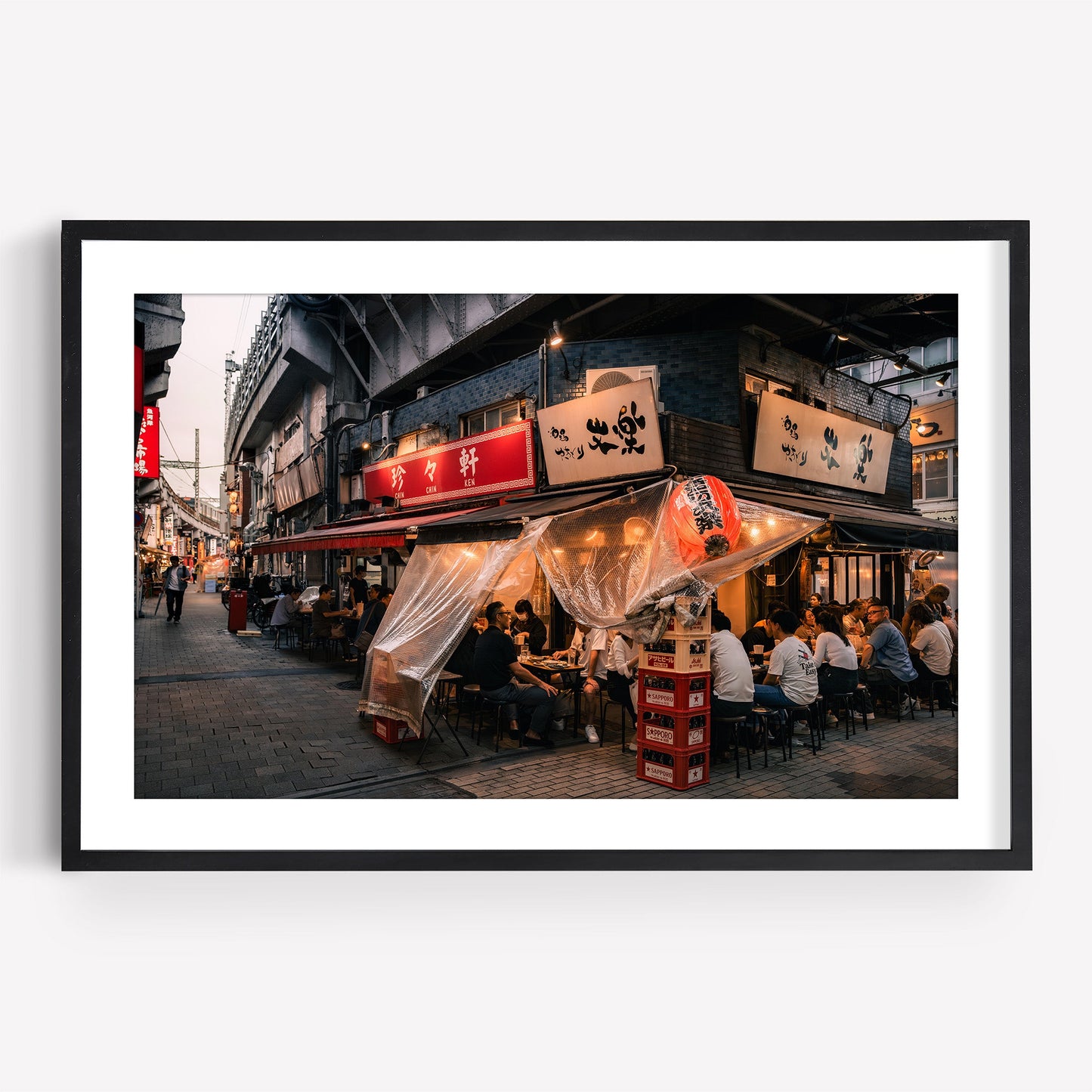 Framed photo, "Flavors Of Ueno": a lively Japanese street restaurant at dusk with diners and glowing lanterns.