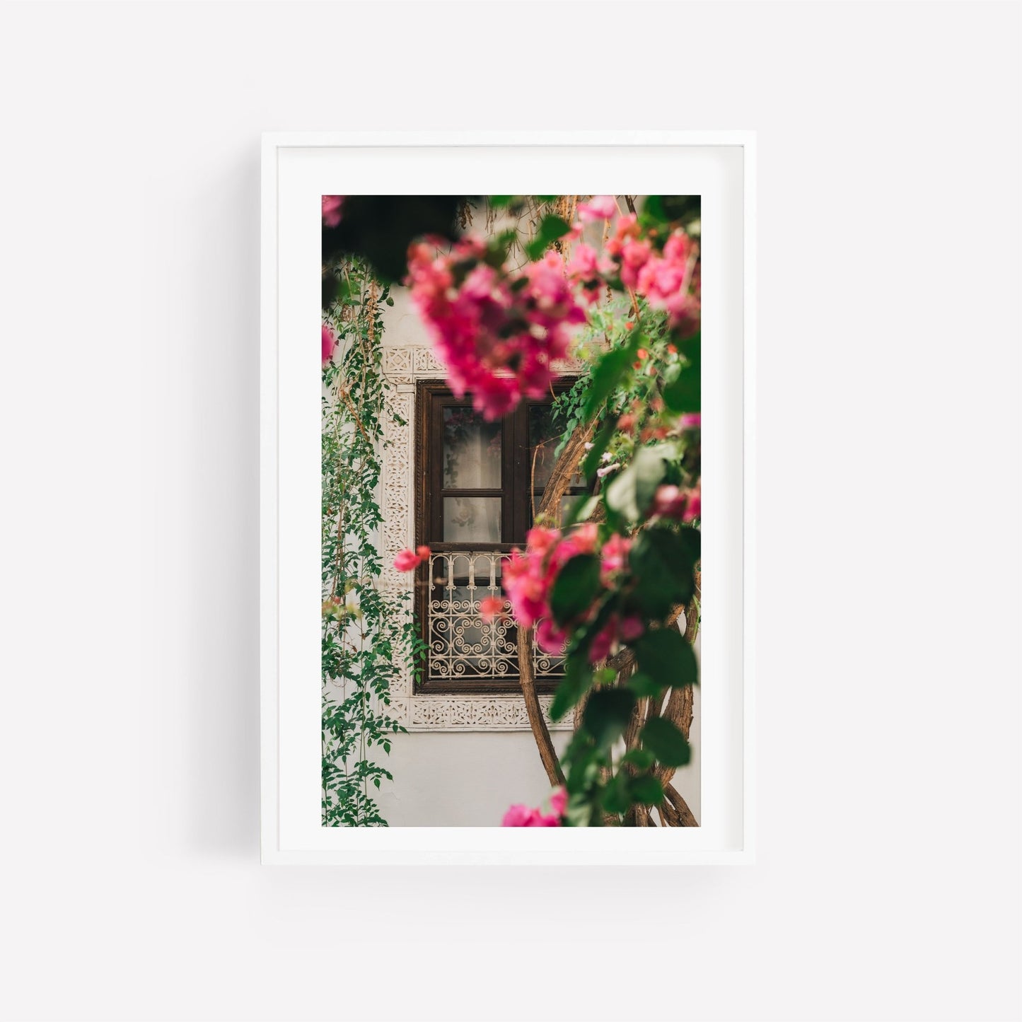 Floral Riad: A framed photo of a window with ornate details, pink climbing flowers, and lush green foliage.