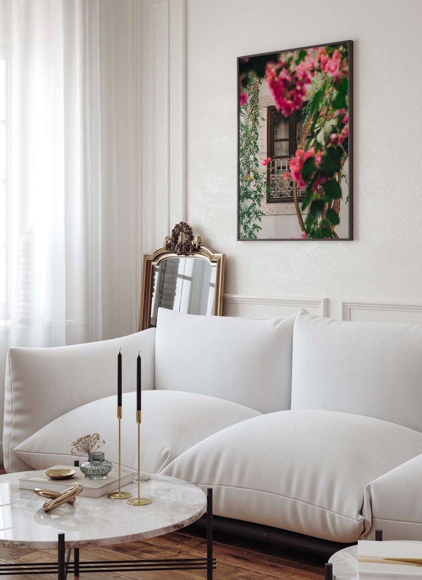 Elegant living room with white sofa, round marble table, gold candle holders, and Floral Riad artwork on the wall.