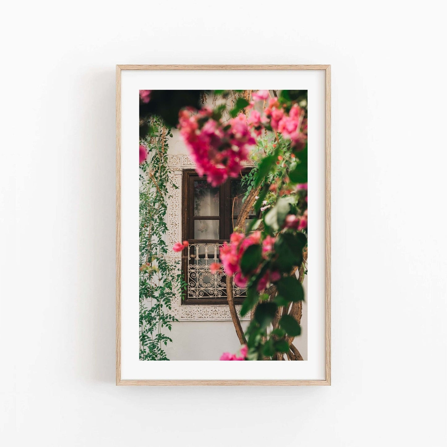 Framed Floral Riad photo features a window with ornate grillwork, partially hidden by pink flowers and greenery.