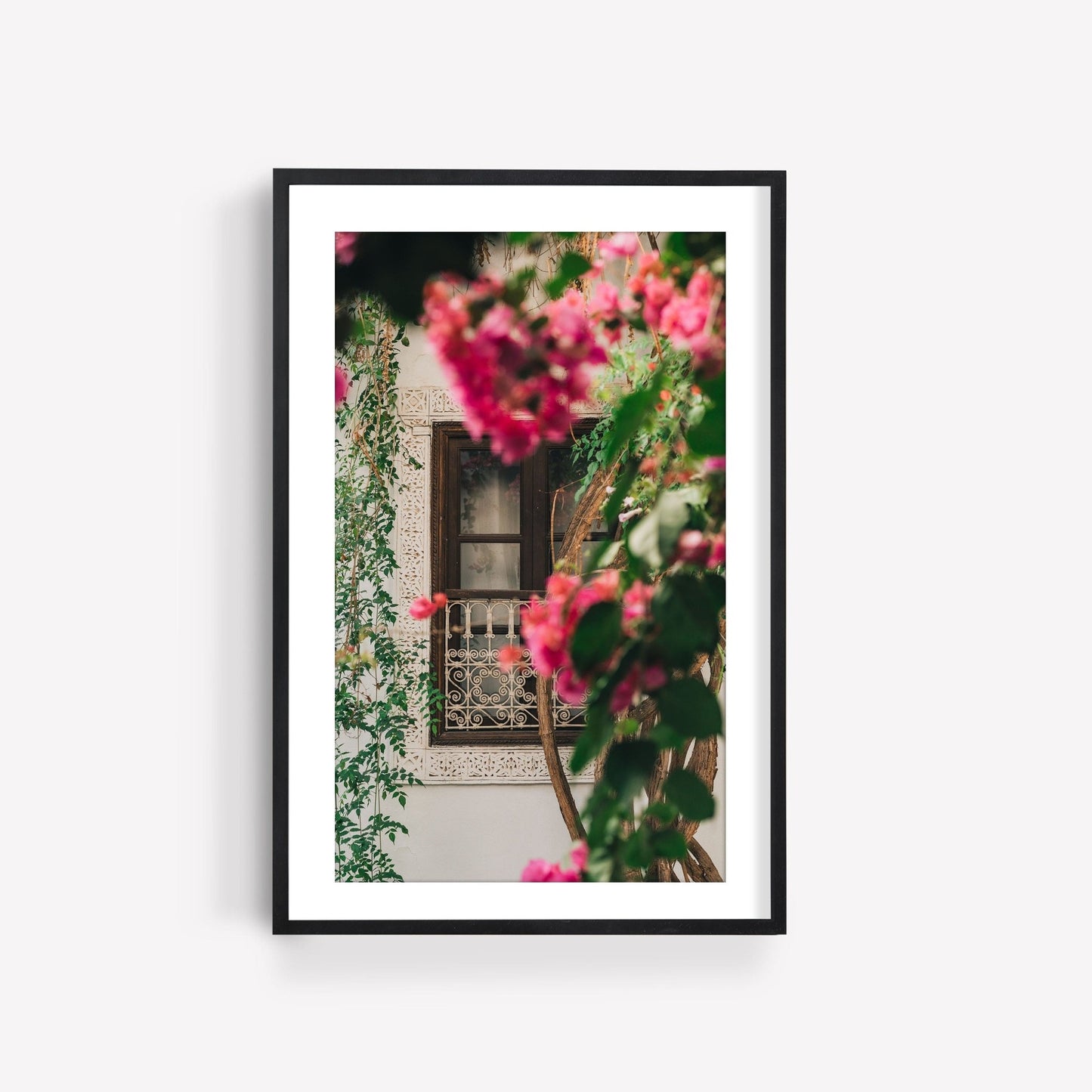 A Floral Riad featuring a framed photo of pink flowers in the foreground and ornate window grilles.