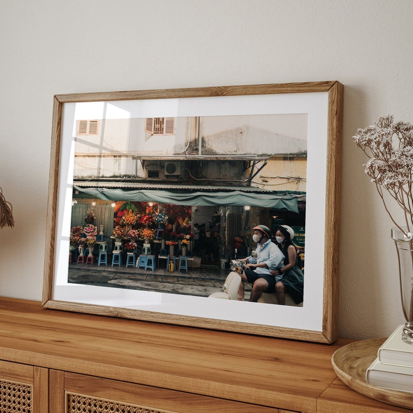 The Floral Ride framed photo on a wooden sideboard shows a street flower stall with two people in hats.