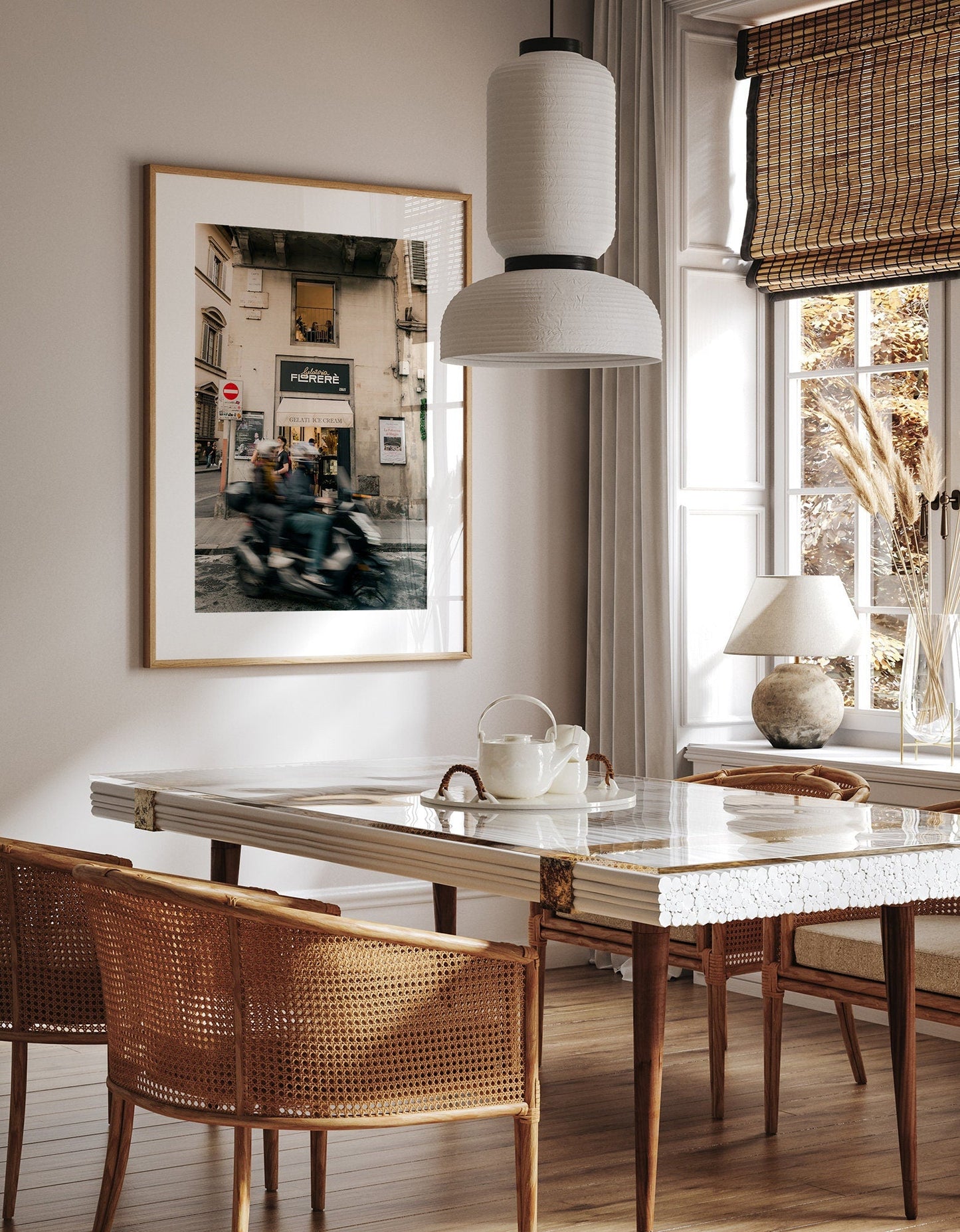 Dining room with a large framed Florence Motorcycle photo, wicker chairs, marble table, and a pendant lamp.
