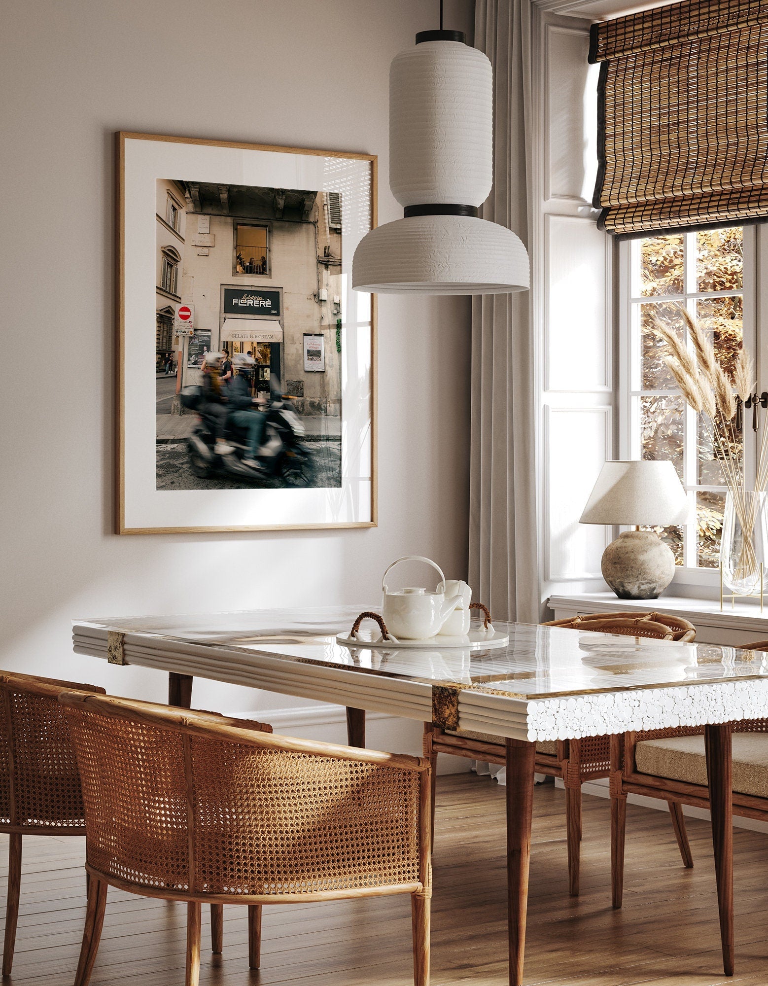 Dining room with a large framed Florence Motorcycle photo, wicker chairs, marble table, and a pendant lamp.