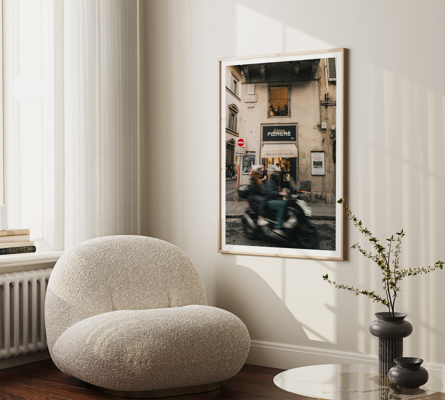 Cozy room with a round chair, small table, and Florence Motorcycle wall art. Natural light floods in from large windows.