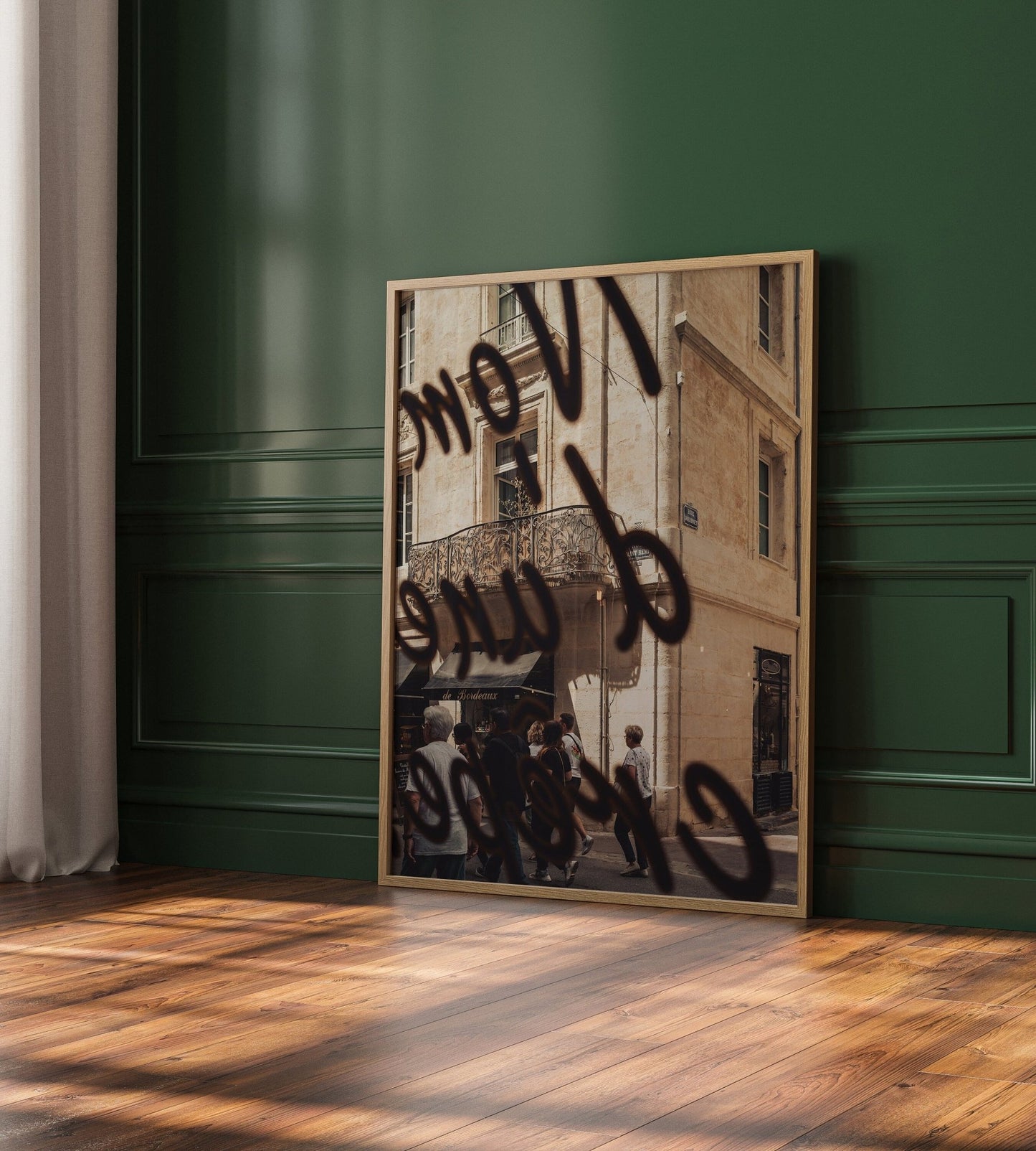 The French Charm mirror reflects a vintage building facade, leaning on a green paneled wall, atop a wooden floor.