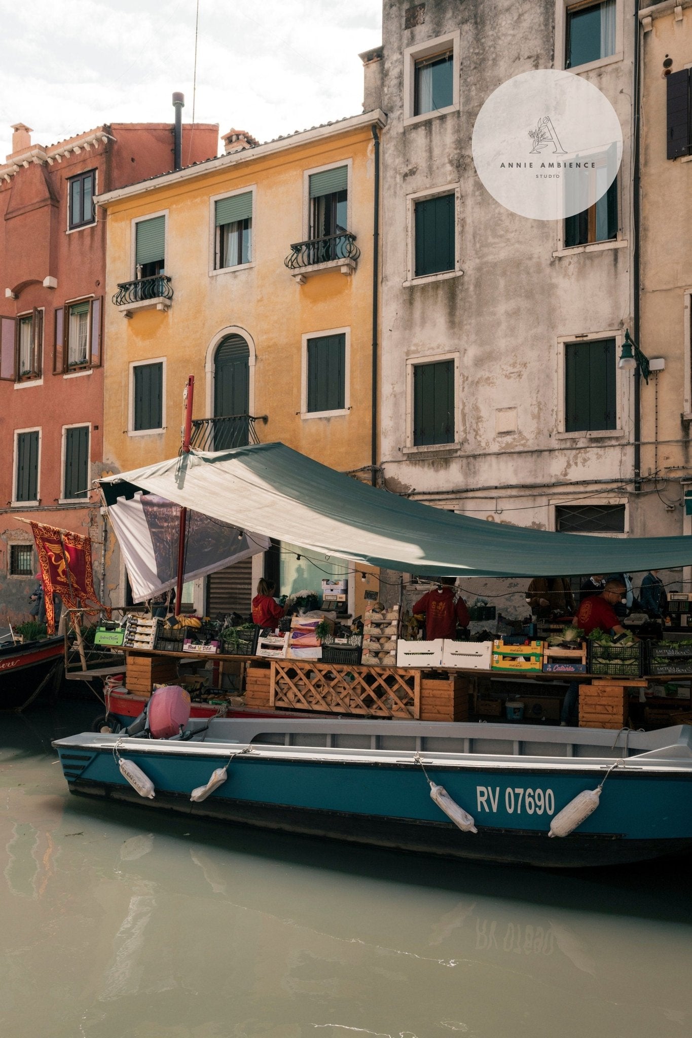 The Fruit Boat displays goods under a tarp along the canal, bordered by colorful buildings.