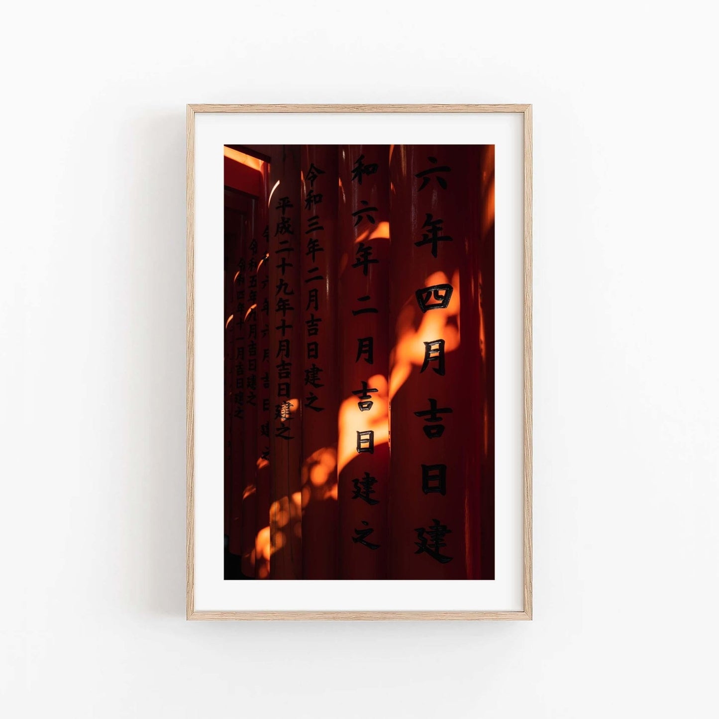 Framed photo Fushimi Inari Taisha II features red pillars with Japanese inscriptions against a white wall background.