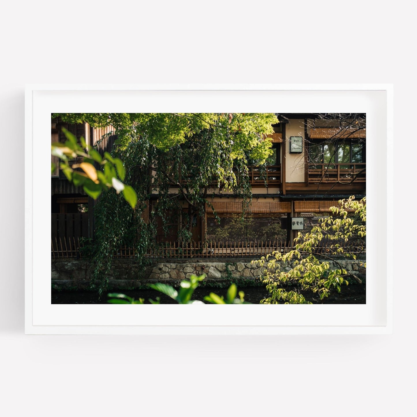 The Gion Greenery features a photo of a traditional wooden building framed by vibrant greenery and a stone wall.