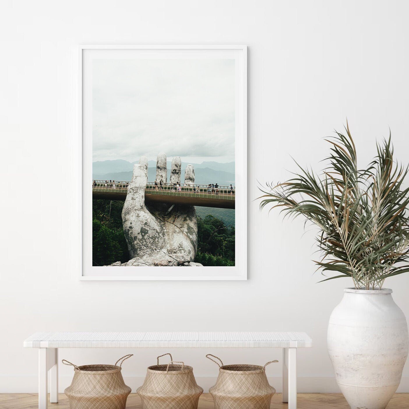 Framed artwork titled Golden Hand Bridge I features a hand sculpture holding a bridge in a minimalist room with plants.