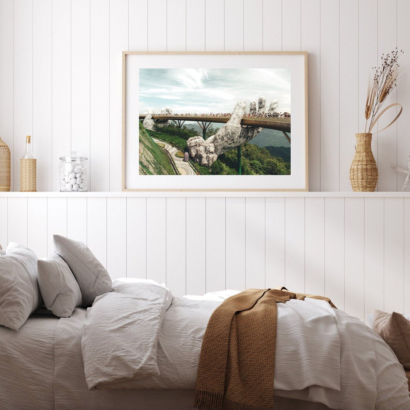A cozy bedroom with the Golden Hand Bridge II framed above a bed with white linens and a brown blanket.
