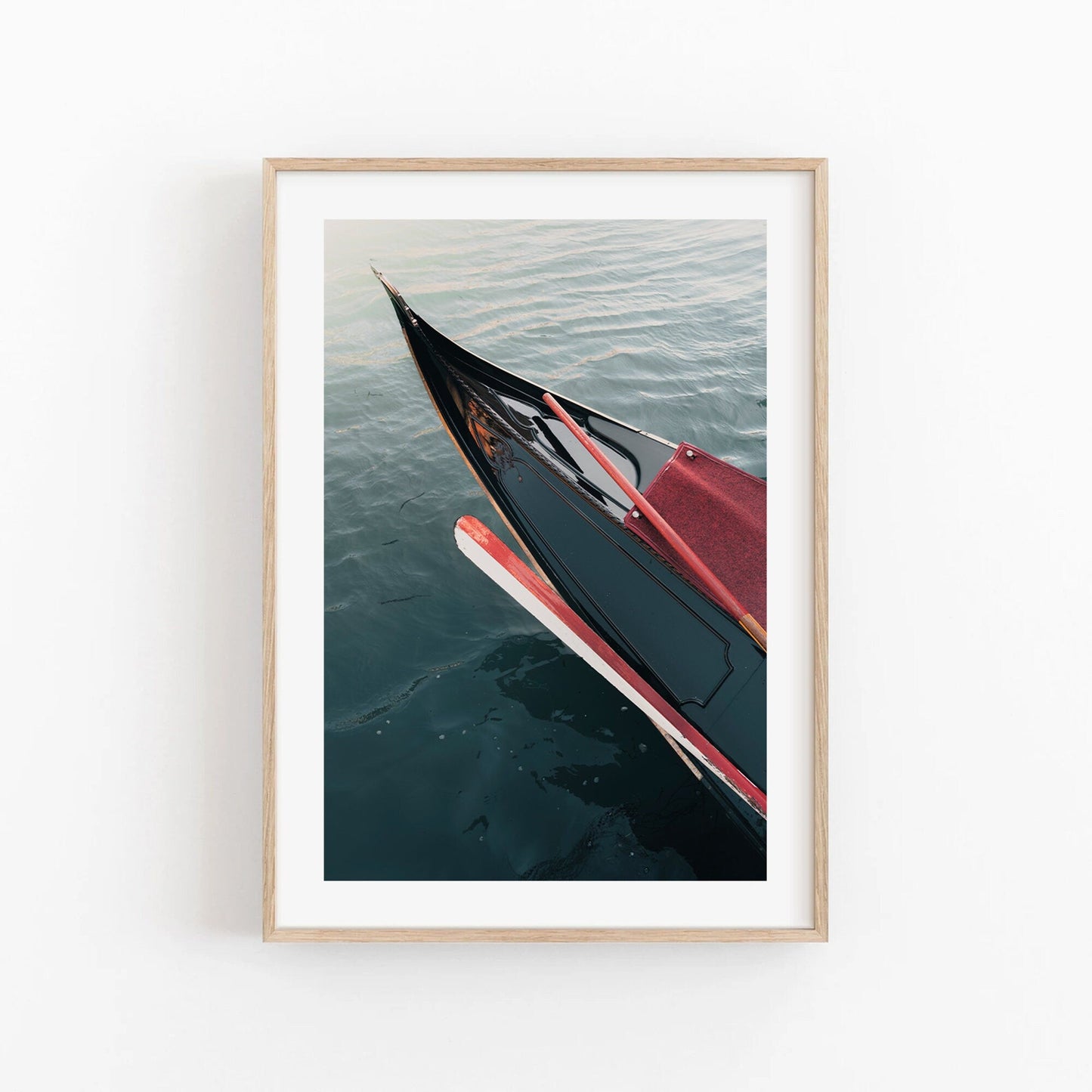 Framed Gondola photo on calm water against a plain white wall.